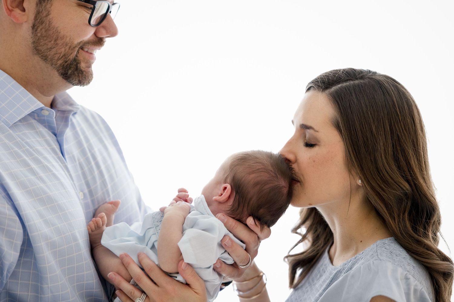 Tender family moment with newborn against white studio background.