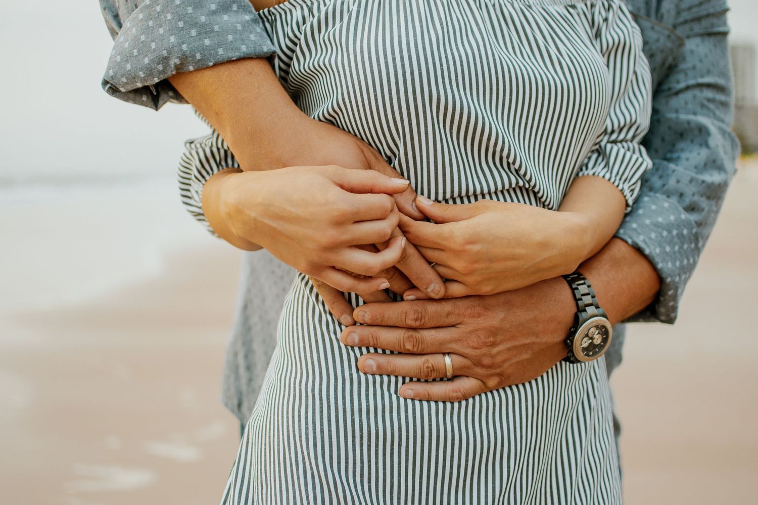 Maternity photography showing hands cradling baby bump in striped clothing.