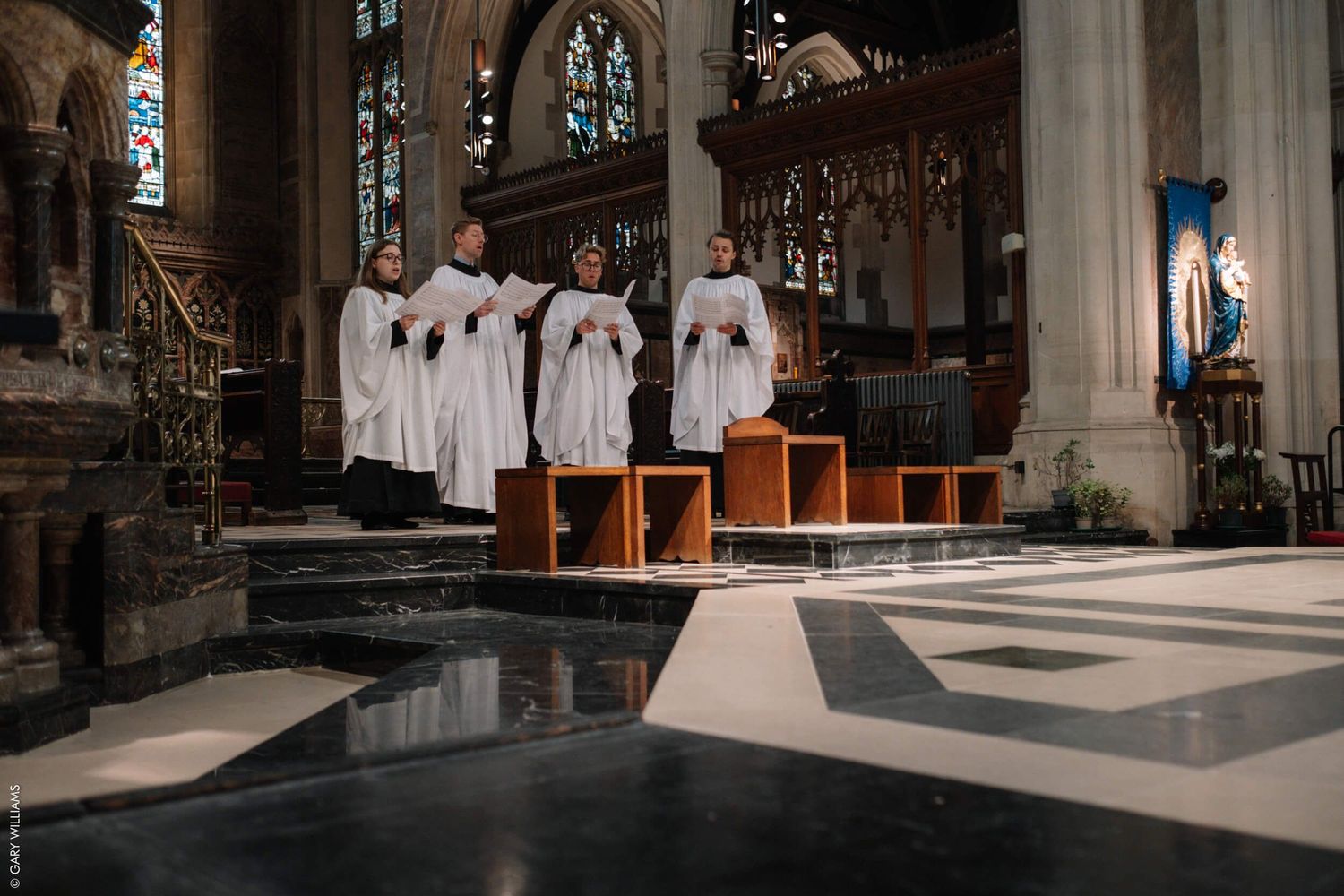 Church choir in white robes standing on steps during a service.