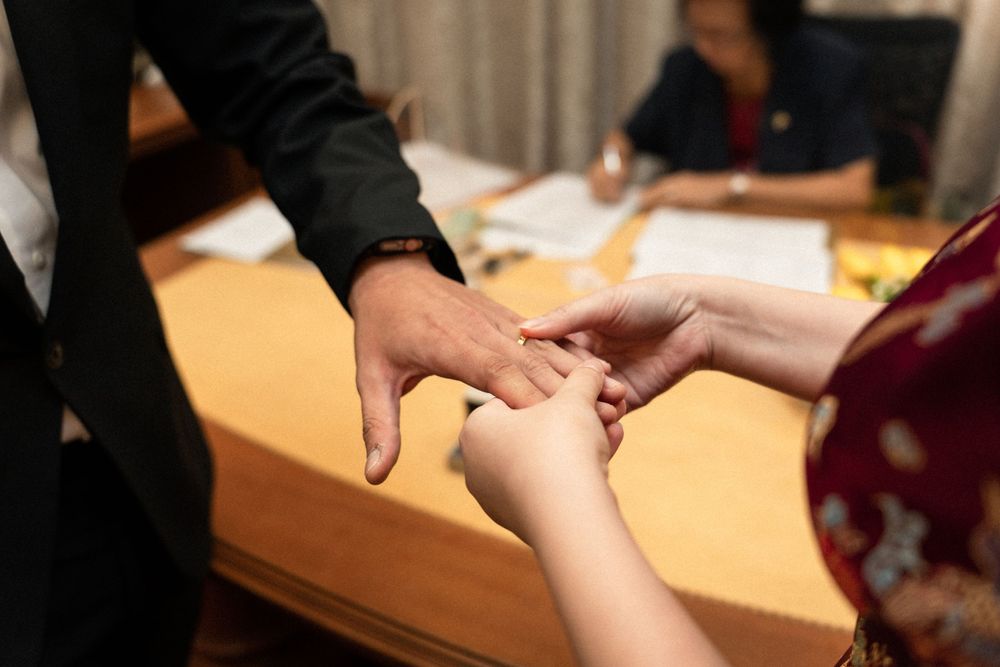 Close-up of hands exchanging ring during traditional ceremony.
