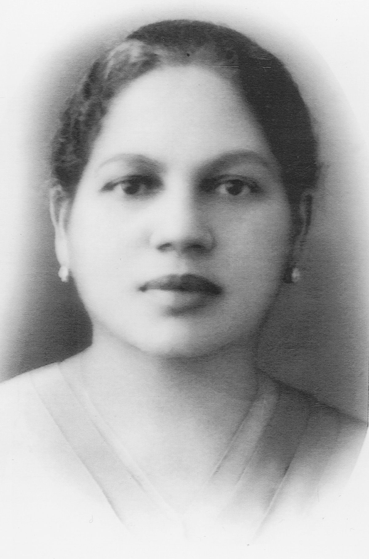 Black and white portrait photograph showing a woman with earrings and neatly styled dark hair in a 1930s style.