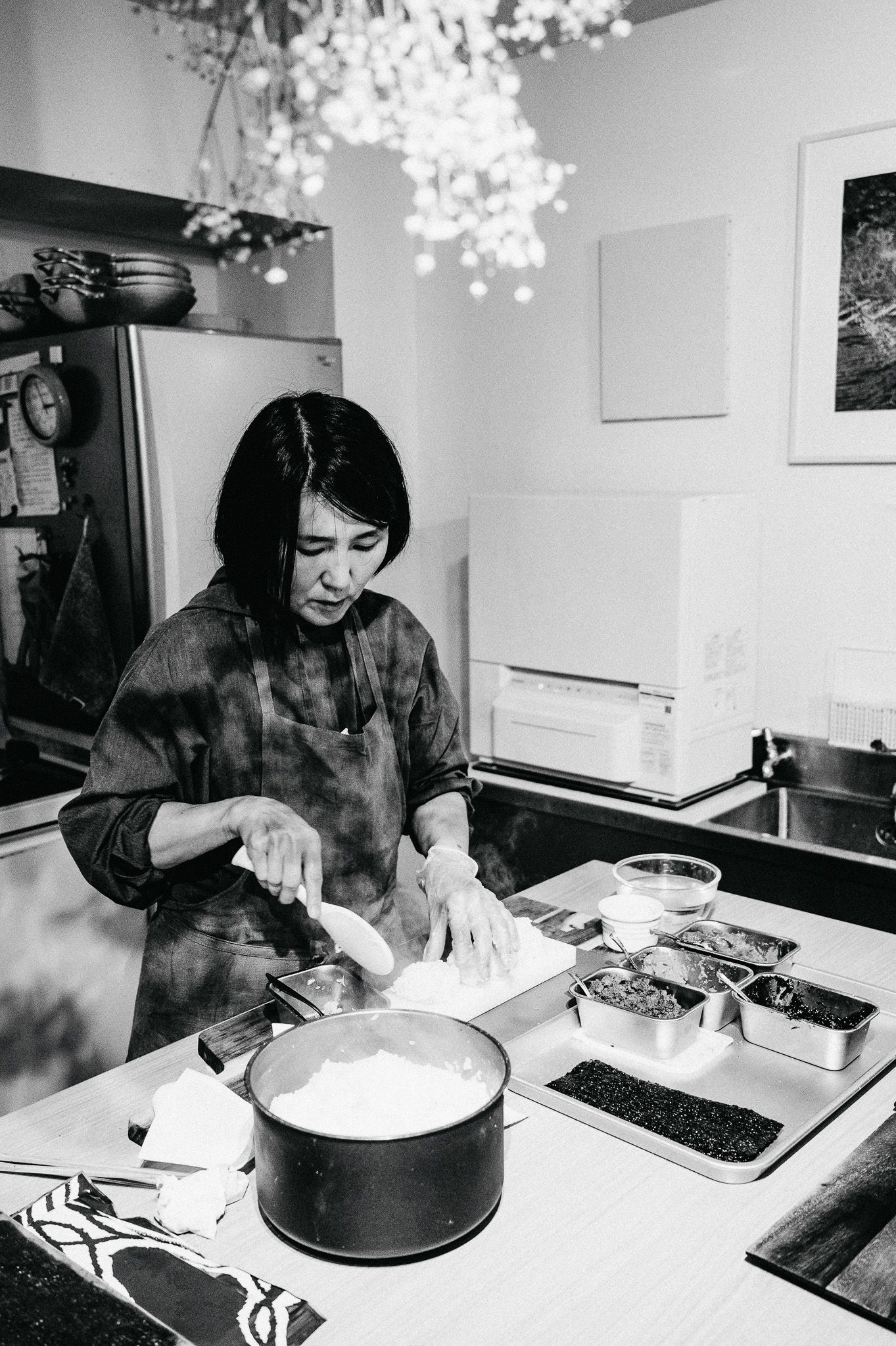 Someone preparing ingredients in a modern kitchen with hanging pendant lights above.