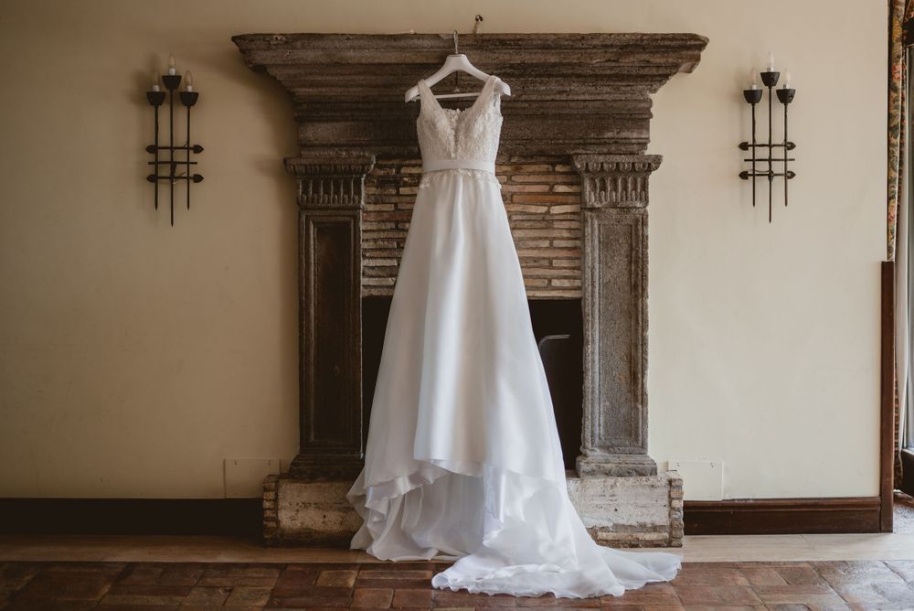Elegant white wedding dress displayed in rustic venue with ornate wooden details.
