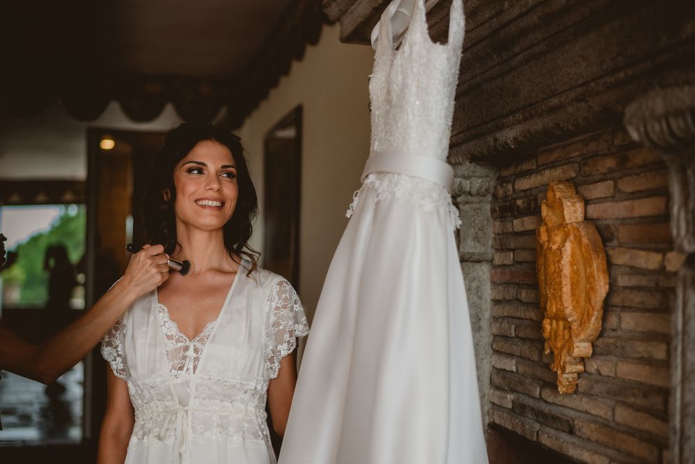 Wedding preparation scene with white bridal gown hanging in rustic wooden interior.