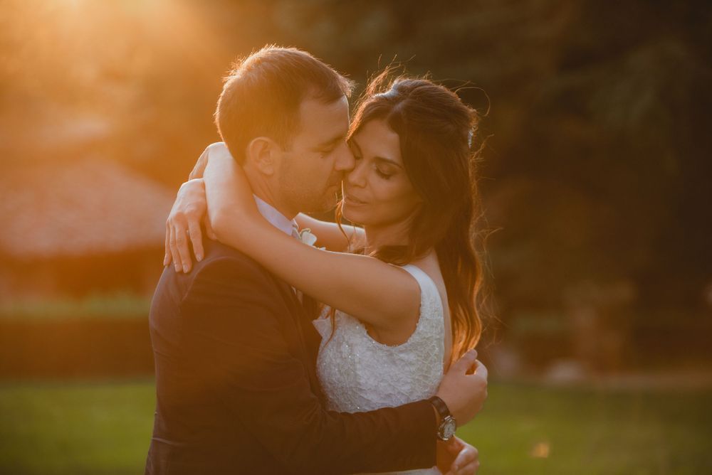 A romantic sunset embrace between newlyweds captured in warm golden light.
