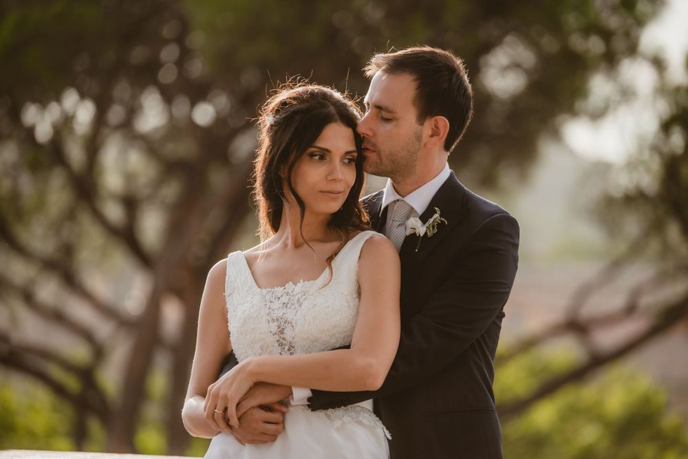 Newlyweds share an intimate moment among trees during golden hour.