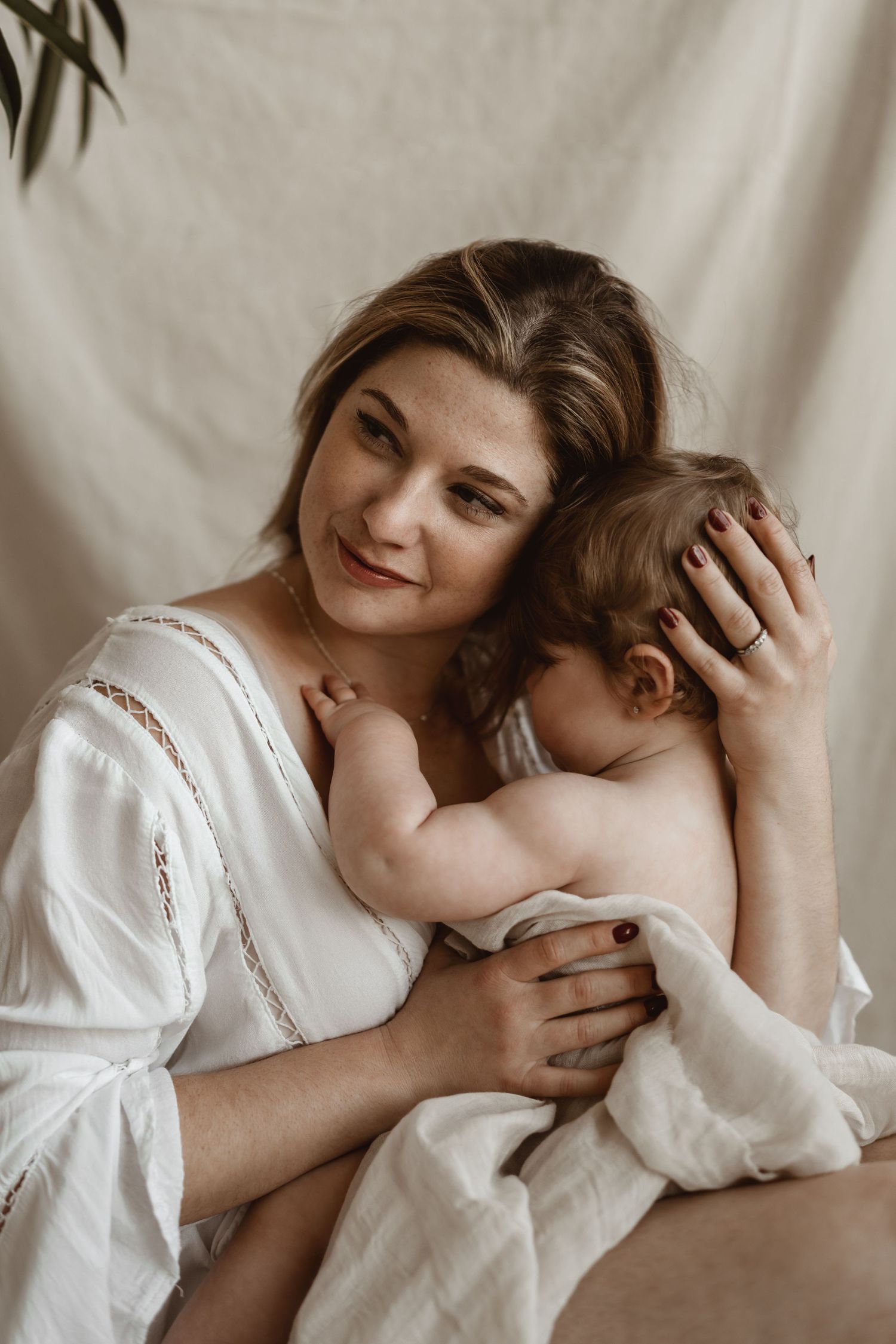Warm portrait of parent and child sharing loving moment against neutral background.