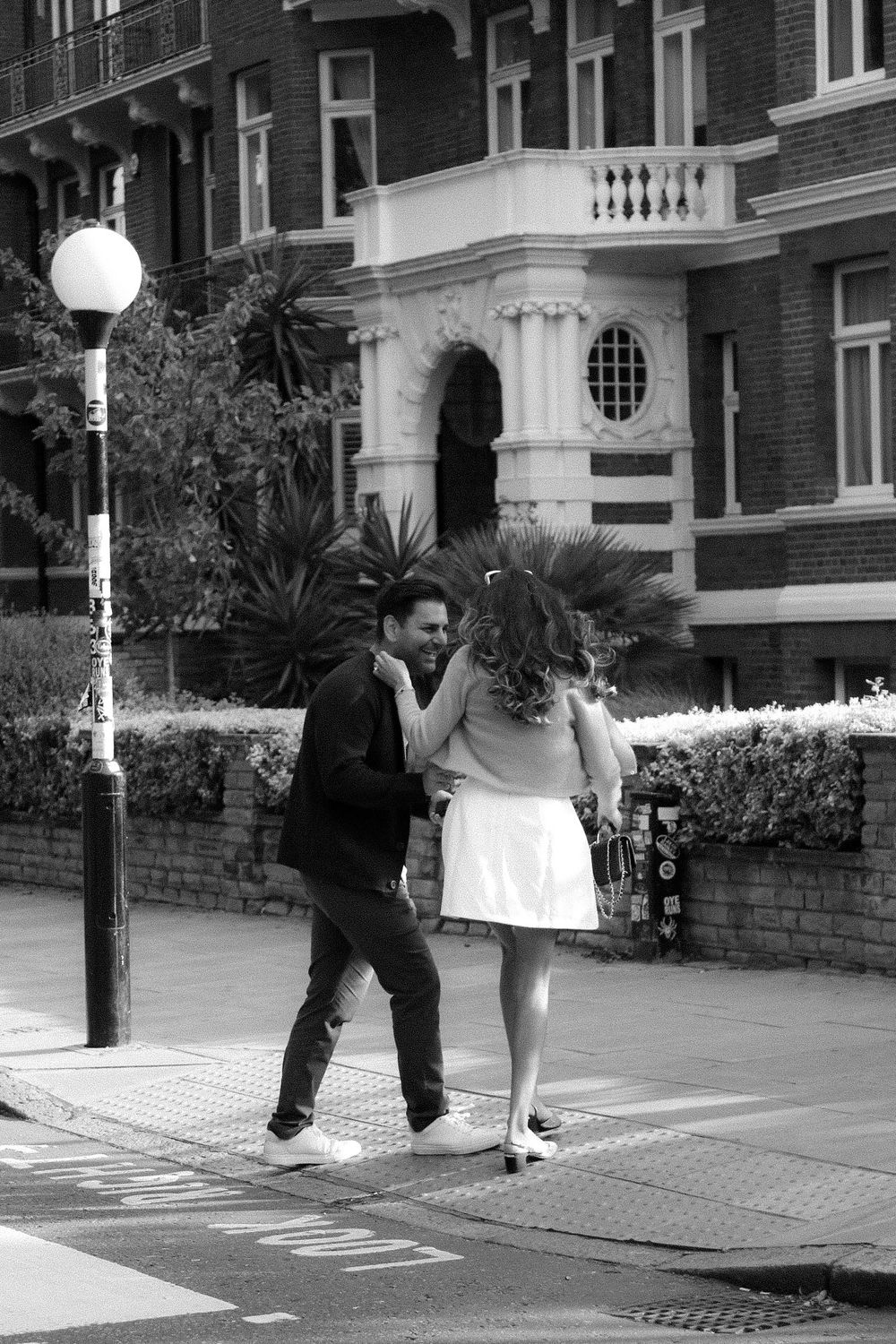 A black and white image of a couple walking together after their proposal moment.