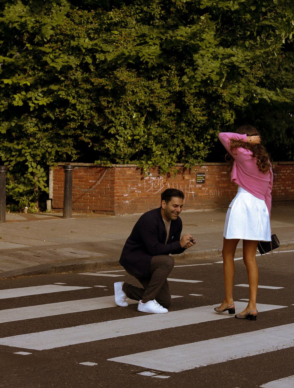 Playful scene of couple recreating Beatles Abbey Road crossing pose.