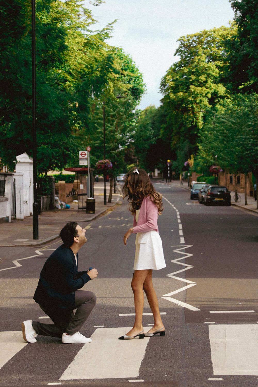 A couple sharing a special moment on a pedestrian crossing with green trees in the background.