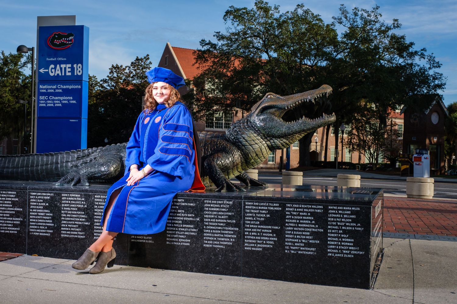 A University of Florida PhD graduate poses for a portrait in her cap and gown in front of the Bull Gator.