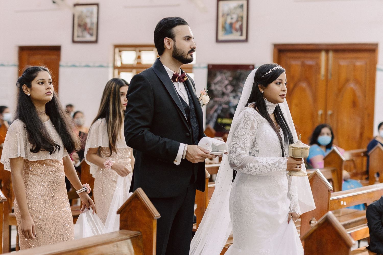 Wedding ceremony in a bright church interior with wooden doors and white walls.