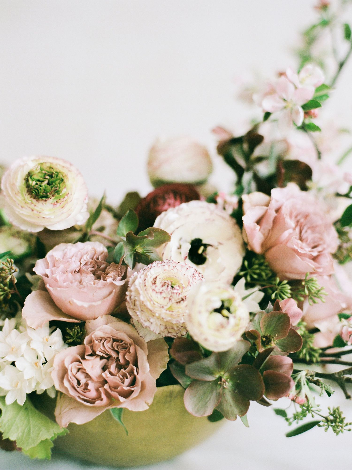 Romantic floral arrangement with blush pink roses and white ranunculus in soft, vintage styling.