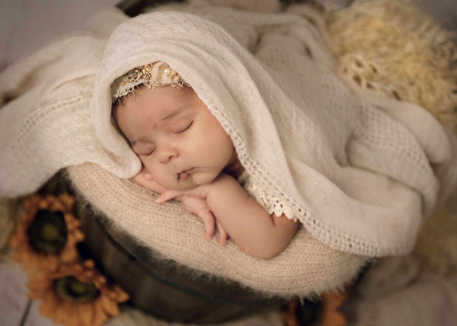 A sleeping newborn wrapped in soft cream-colored textiles sleeping peacefully . Professional newborn photographer, Townsville.