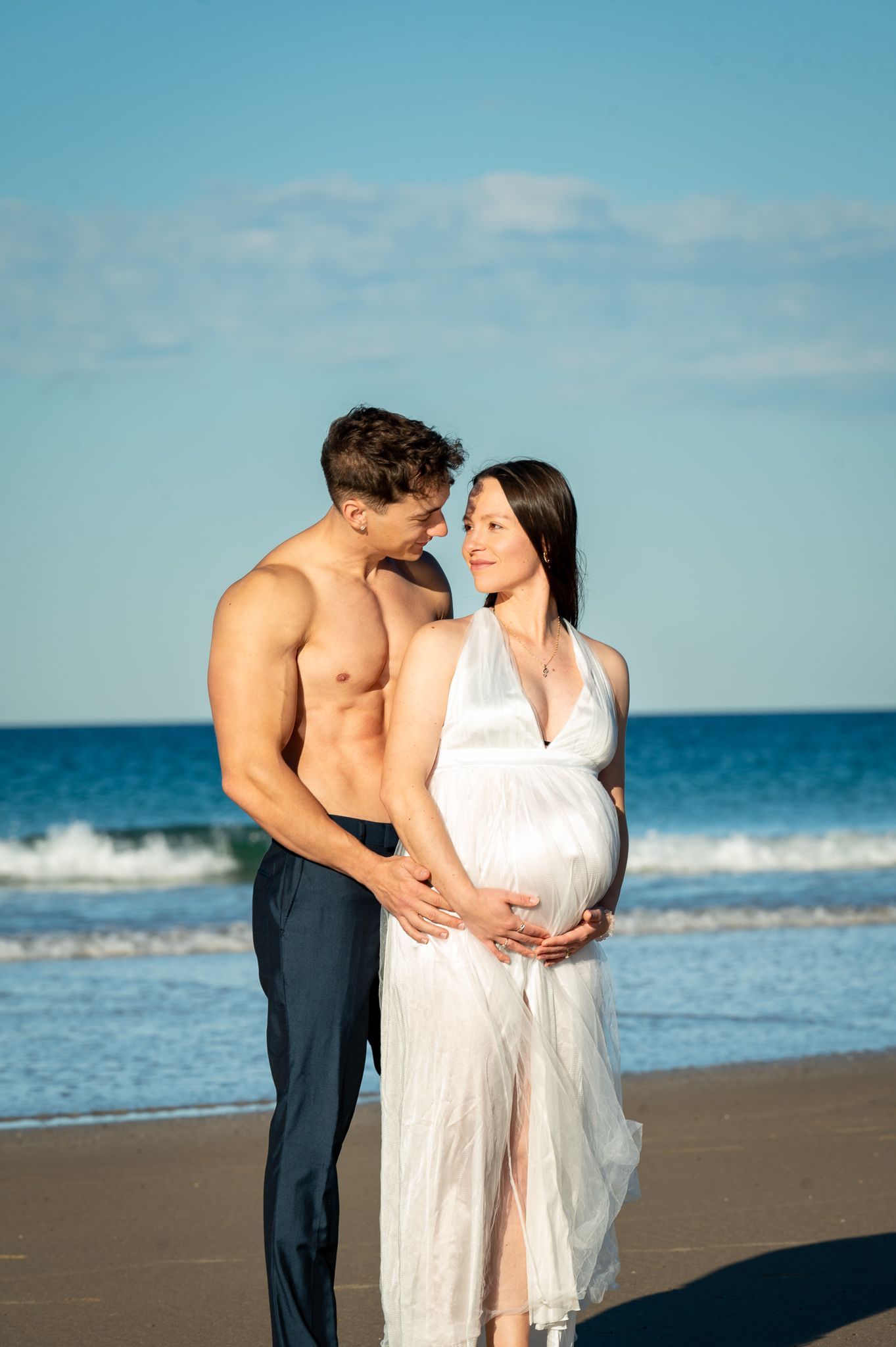 husband and wife celebrating their newborn baby soon to be coming in to this world at the beach