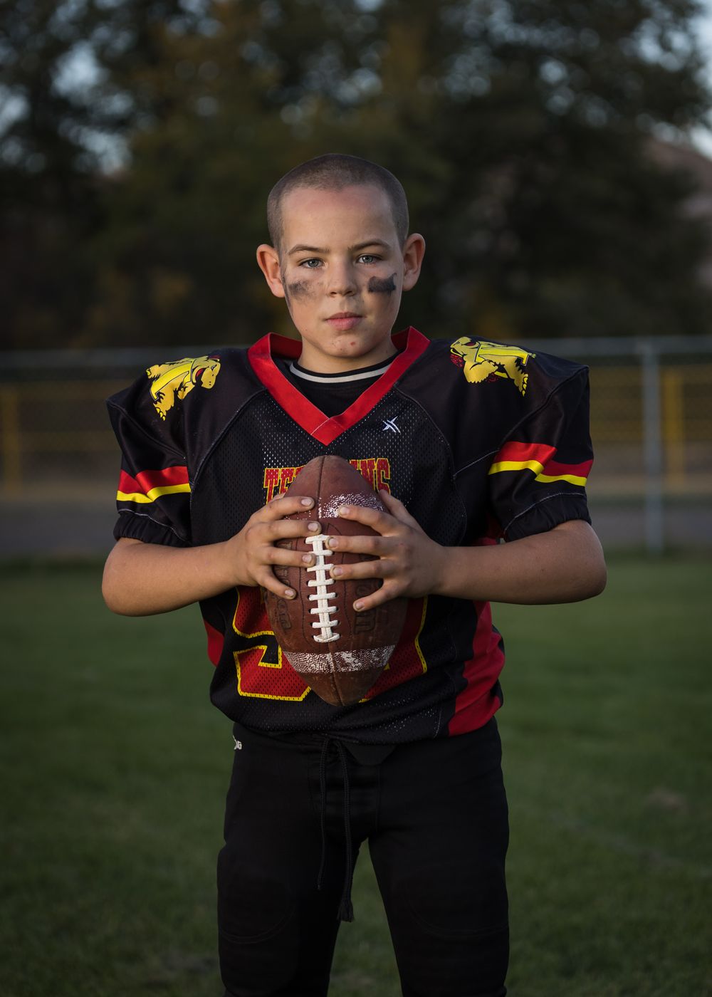 Youth athlete holding football in Terrapins black and red uniform.