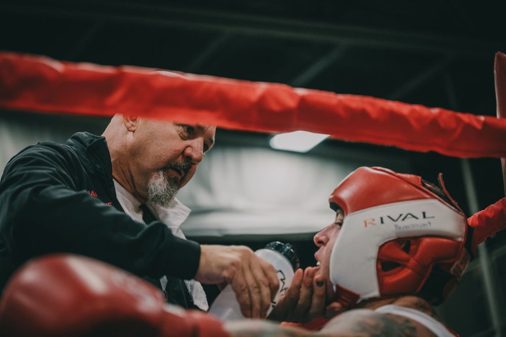 Coach giving instructions to boxer between rounds in boxing ring.