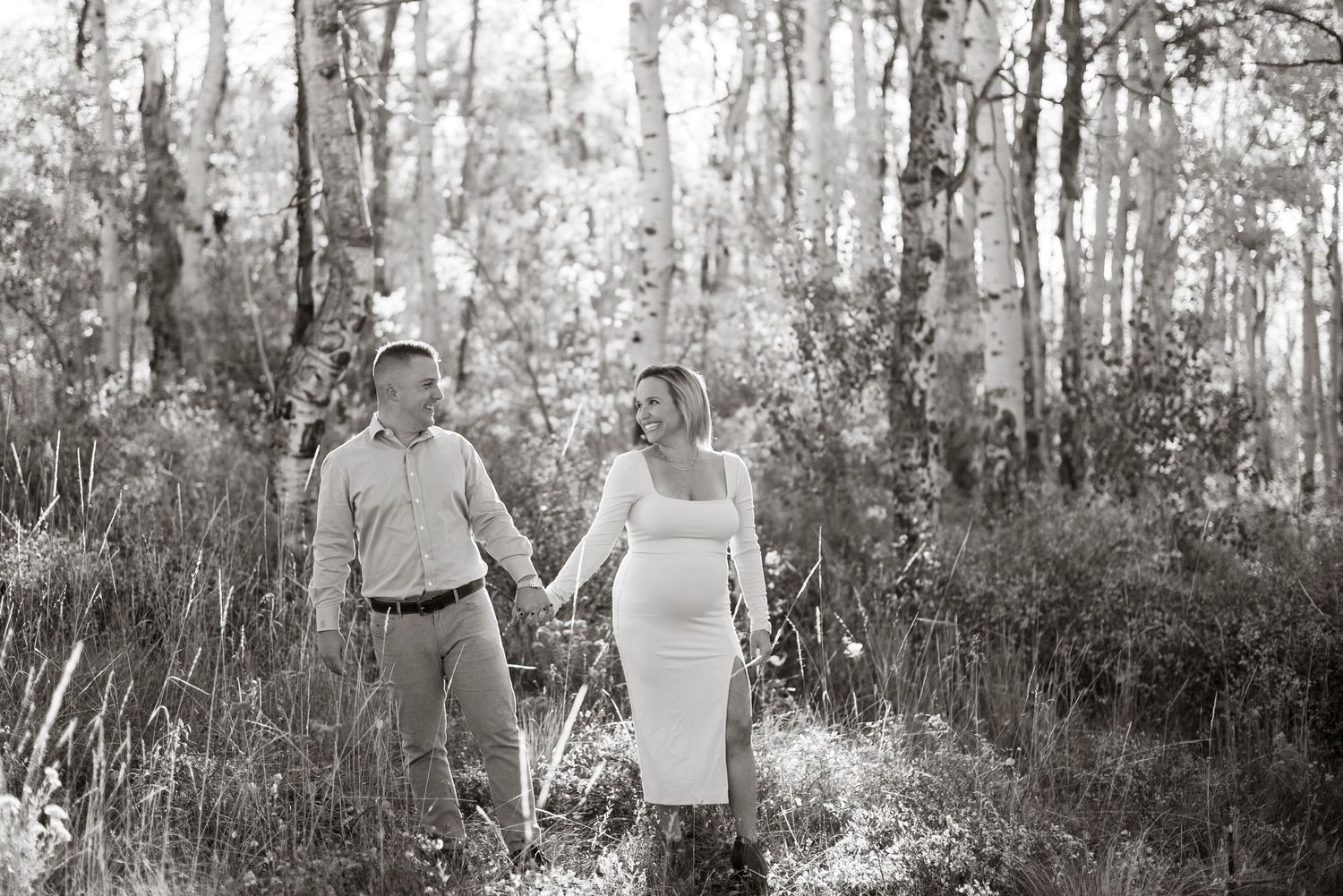 Romantic engagement photos in sunlit forest setting.