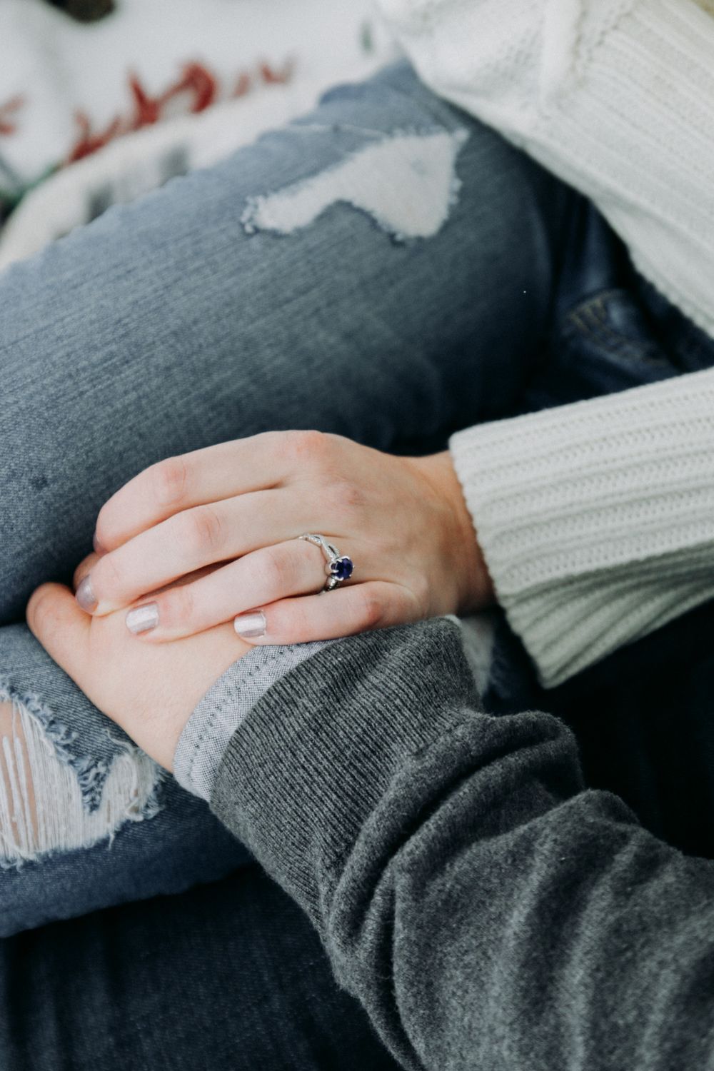 Close-up series showing hands with an engagement ring resting on distressed denim jeans.