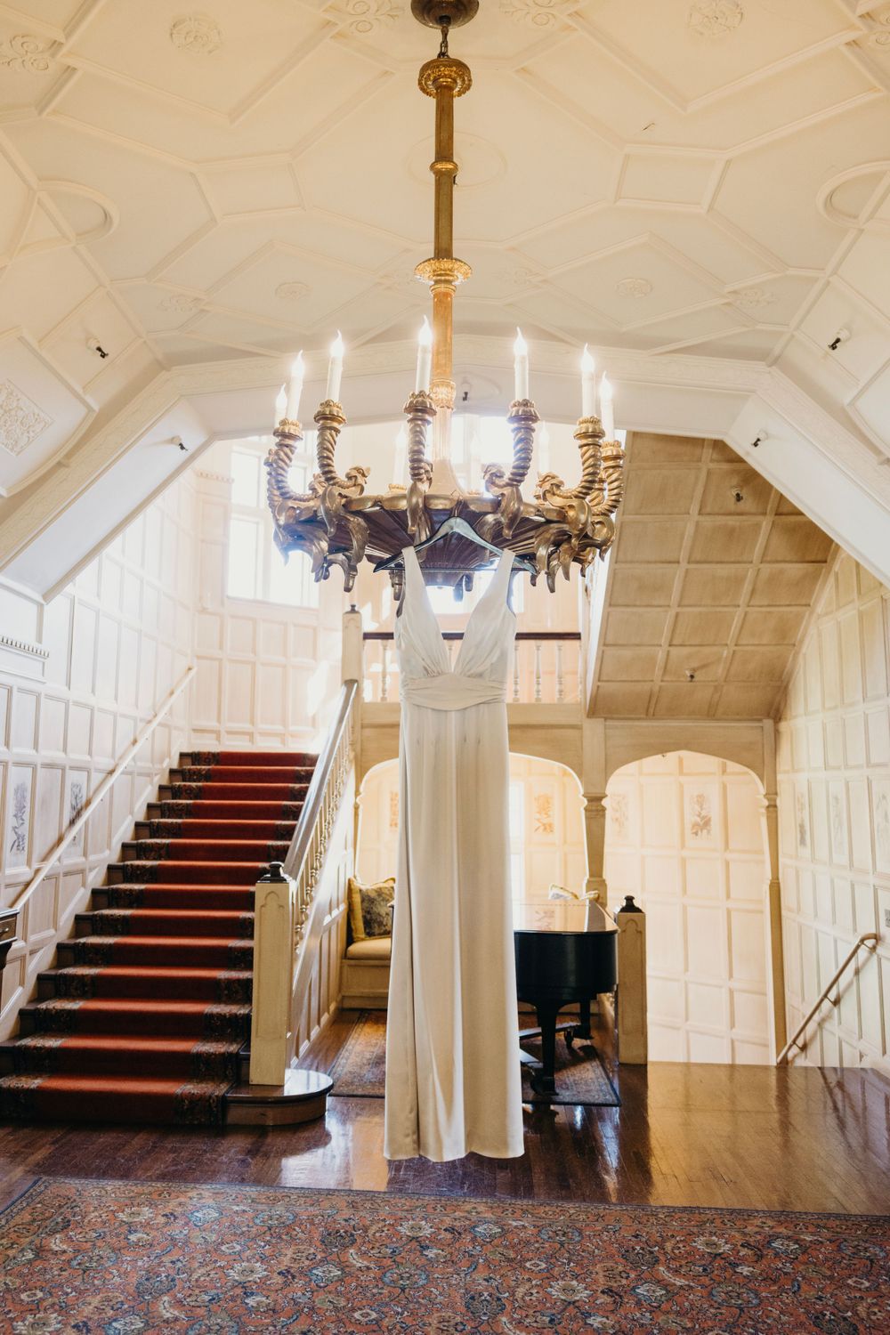 Grand white interior space with chandelier and red-carpeted staircase.