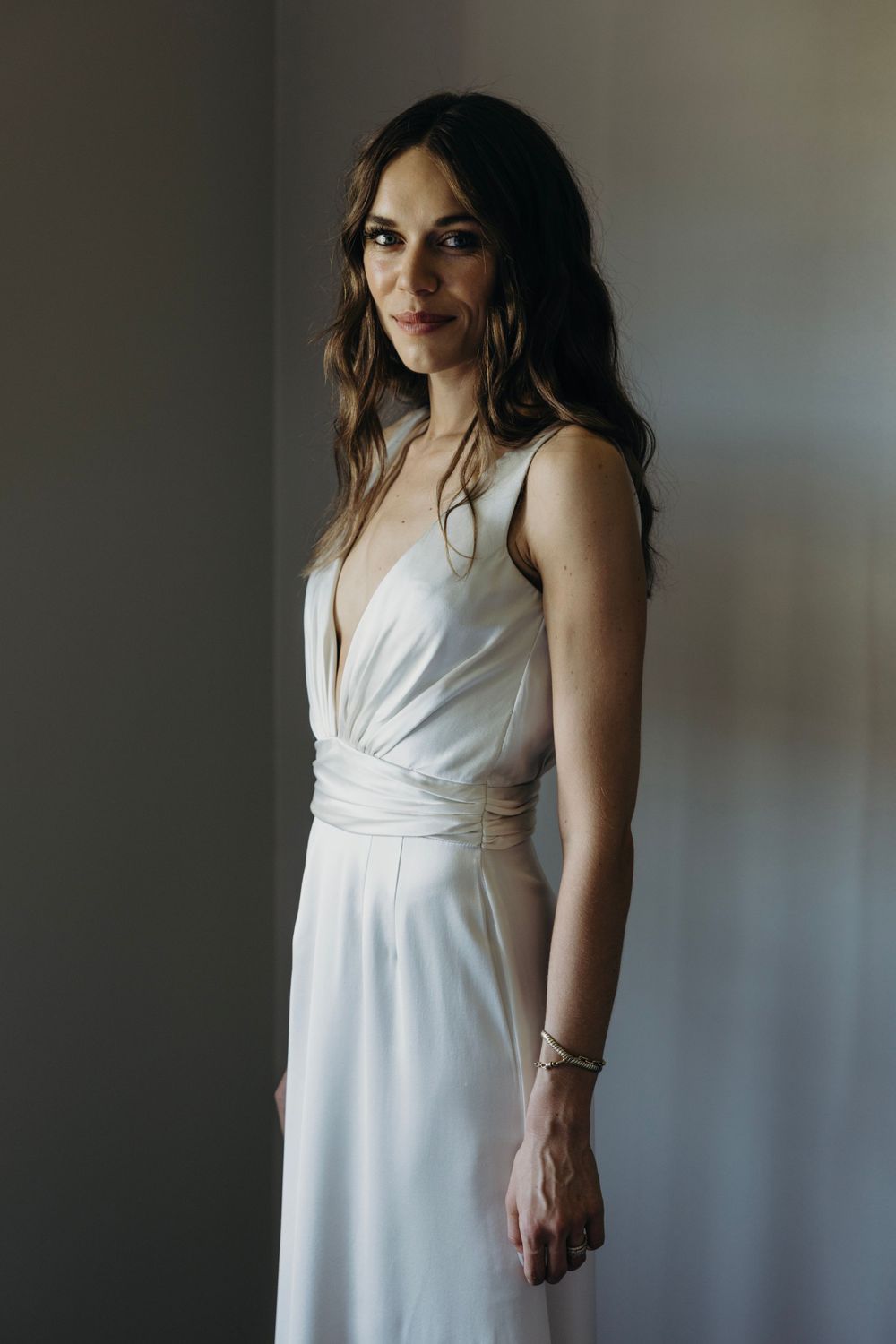 Ethereal portraits of someone in a flowing white dress against grey walls.