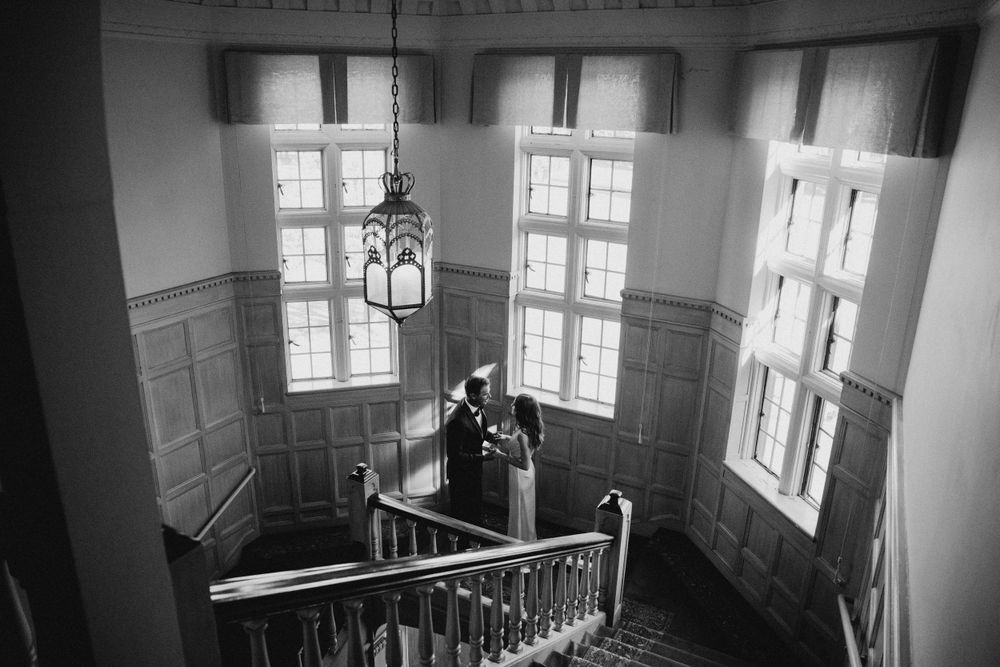 Black and white photo of a couple on an elegant staircase in a historic building.