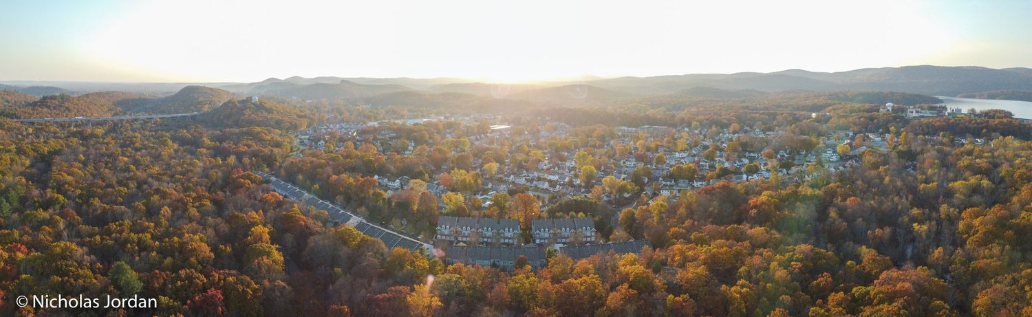 Autumn aerial panorama of a city during sunset with trees showing fall colors.