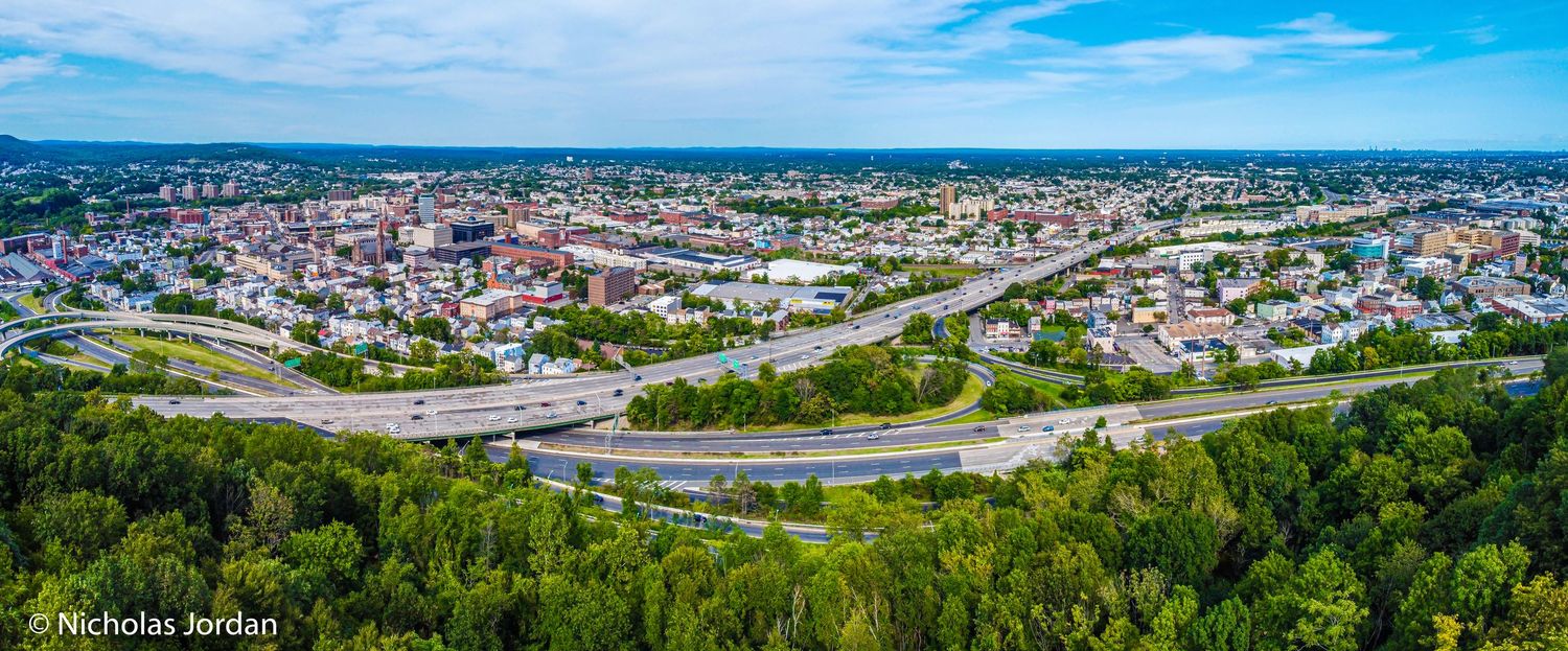 Aerial panoramic view of a city with winding roads and urban development.