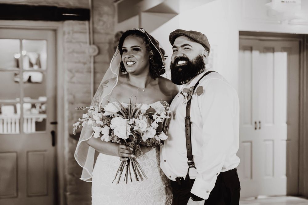 A romantic black and white wedding scene with a couple laughing and embracing outdoors.