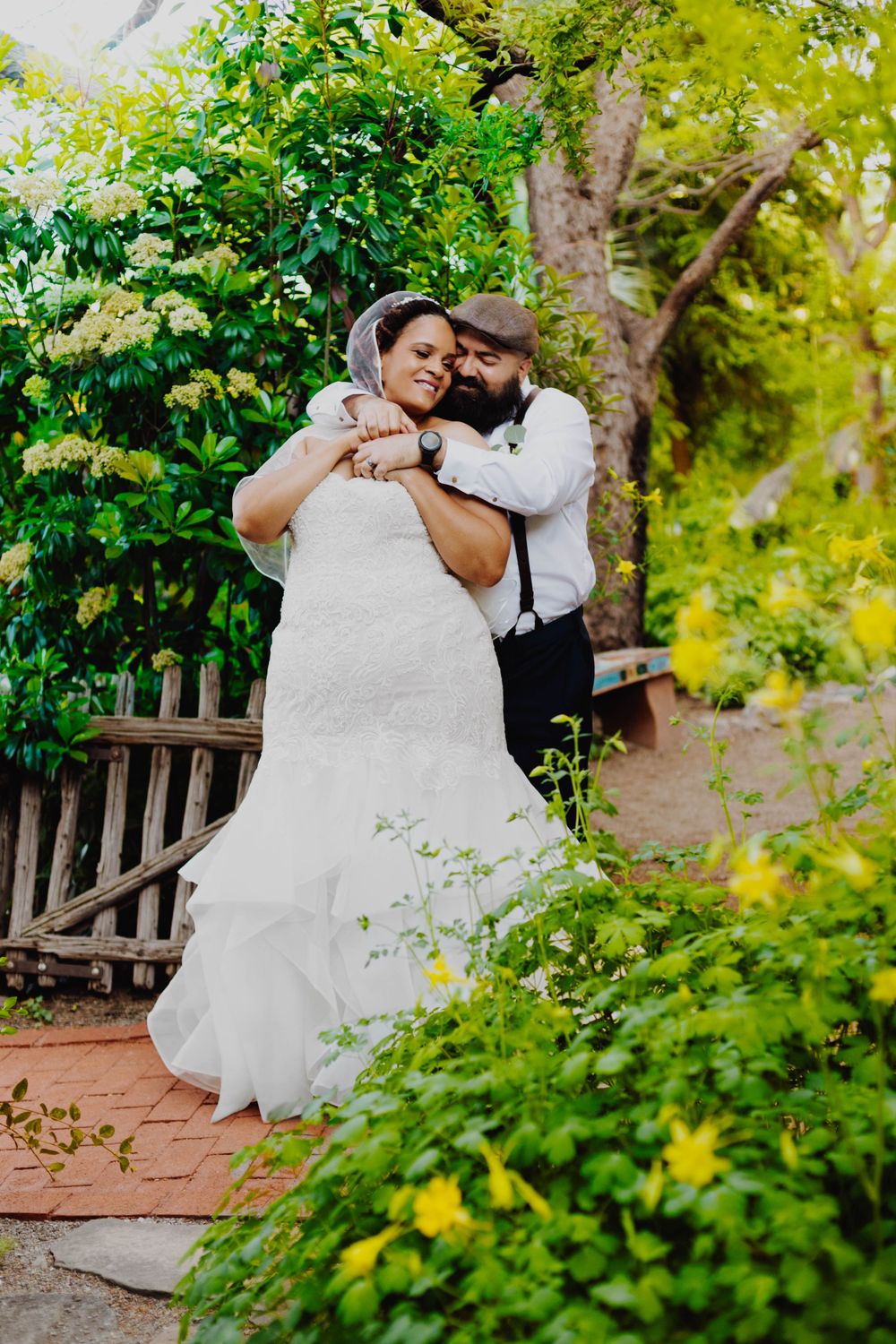Couple embraces romantically in a lush garden setting during their wedding photoshoot.