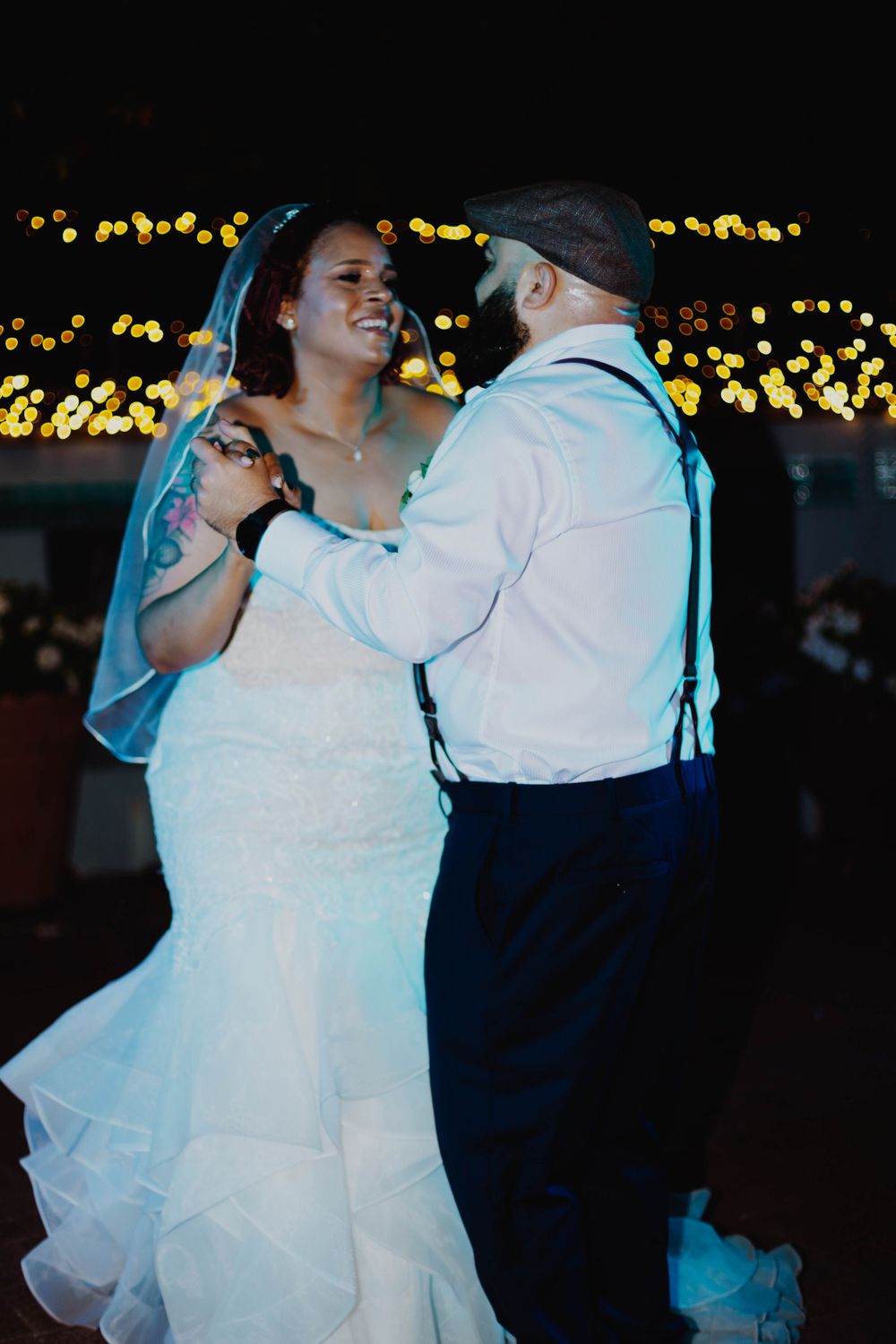 A couple sharing a romantic dance under twinkling lights at their wedding reception.