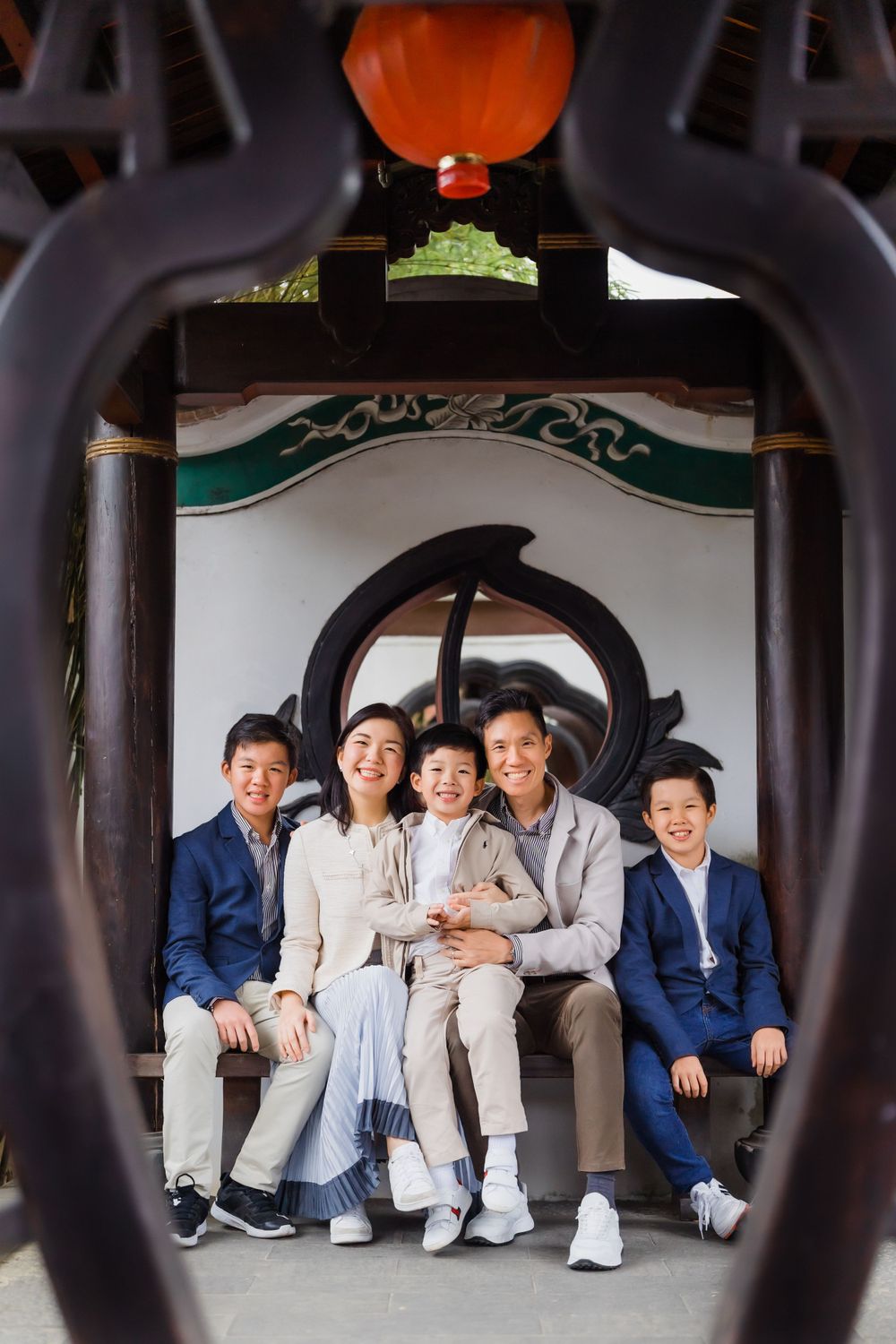 Family portrait framed through decorative archway with orange lantern hanging above.
