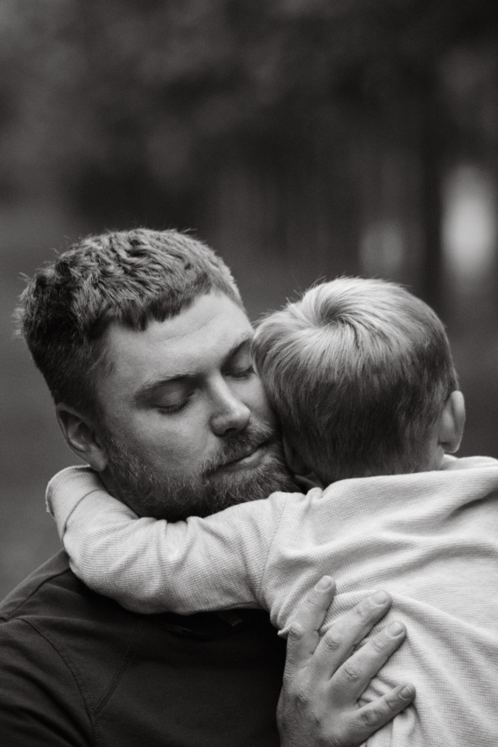 A tender black and white moment captured between a parent and child embracing in a warm hug.