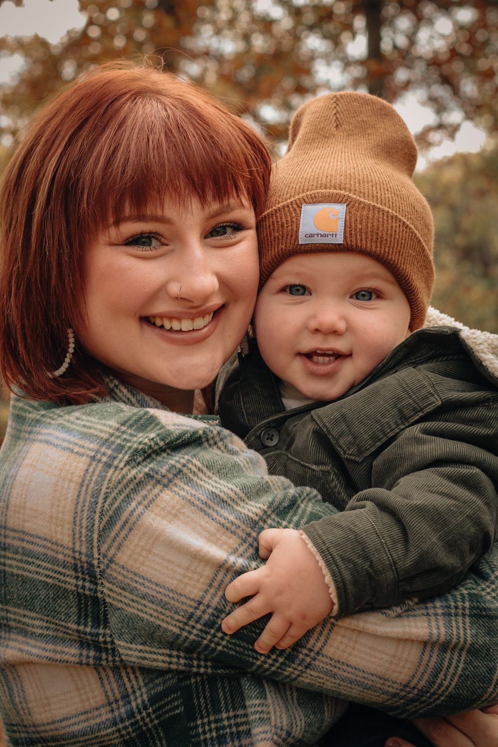 A joyful autumn portrait shows loving affection between parent and child wearing a brown beanie outdoors.