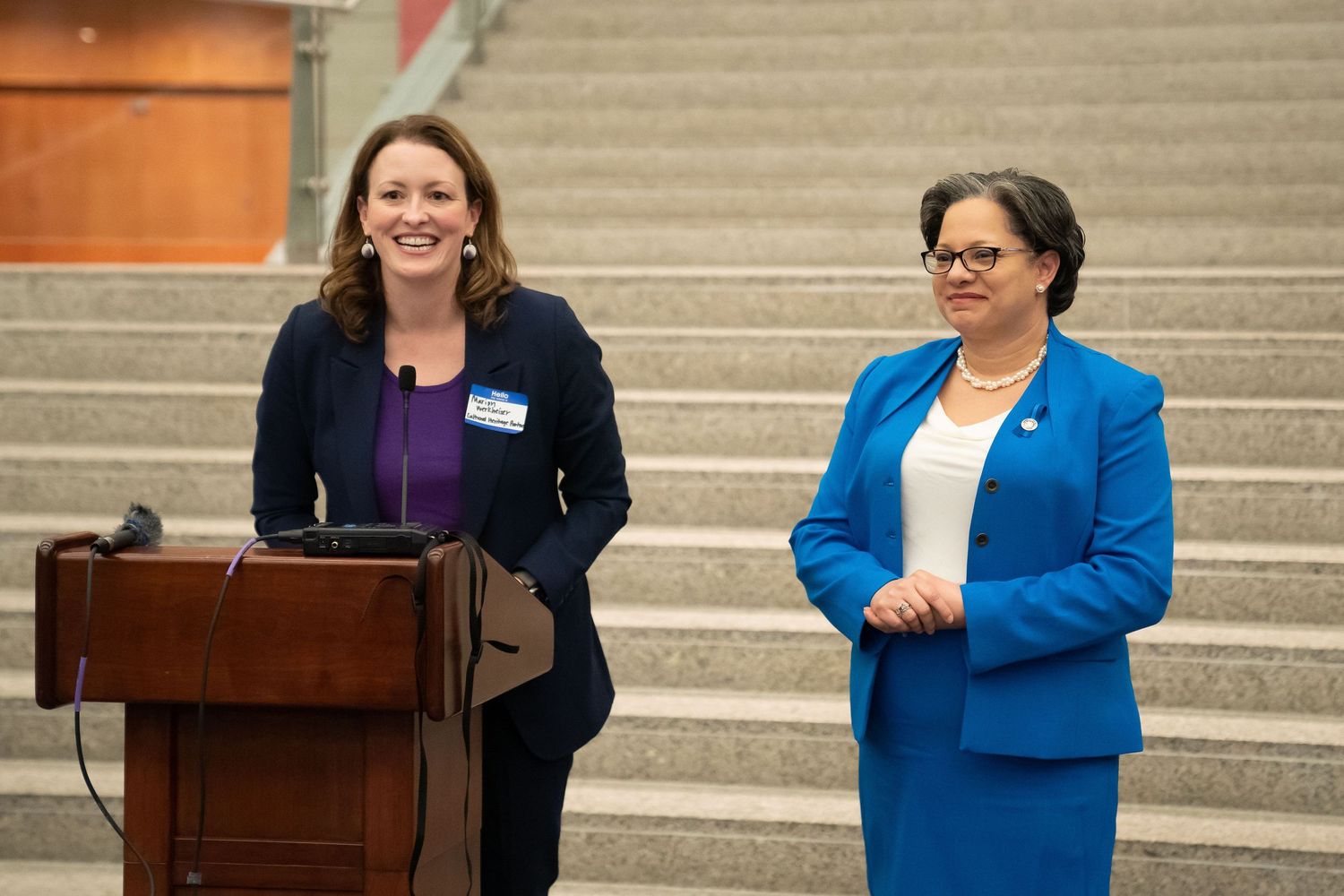 A professional woman in business attire expertly delivering a presentation to an attentive audience