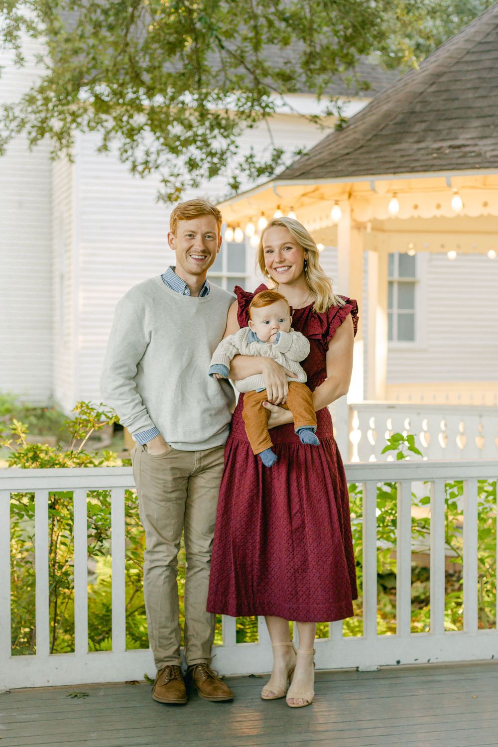 a family photo of a couple and their redhead baby on a porch