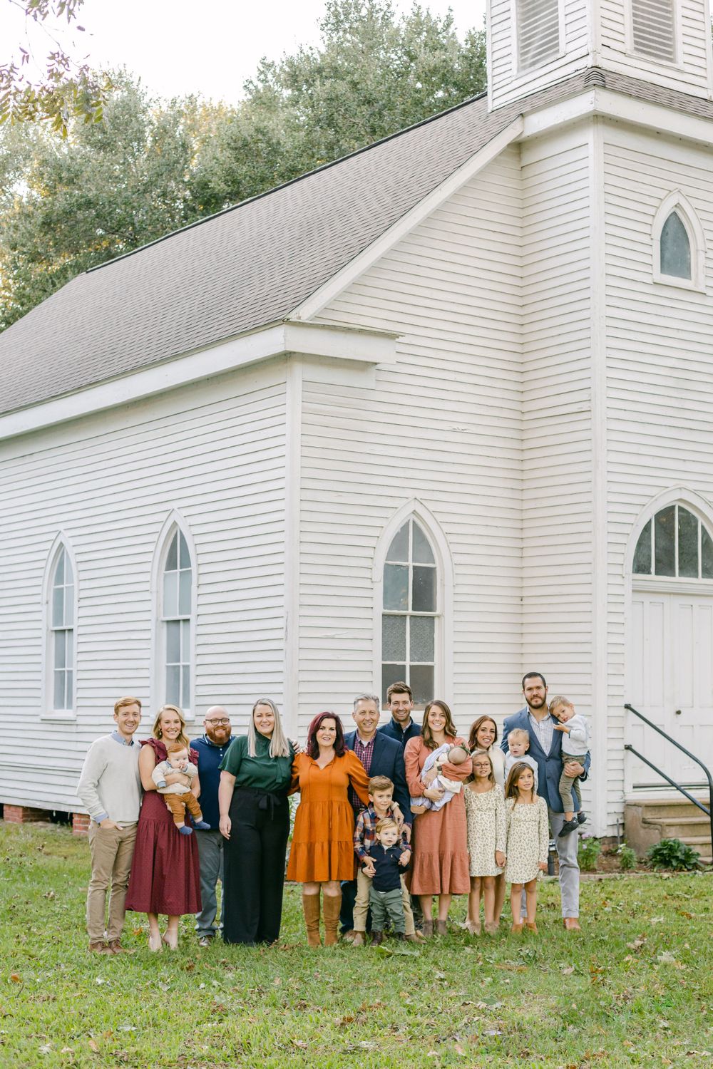 an extended family gathered in front of a white church