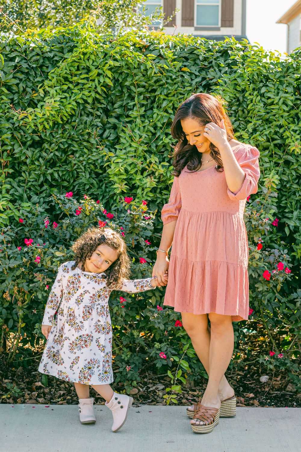 a mom gazes down at her three year old daughter who poses for the camera