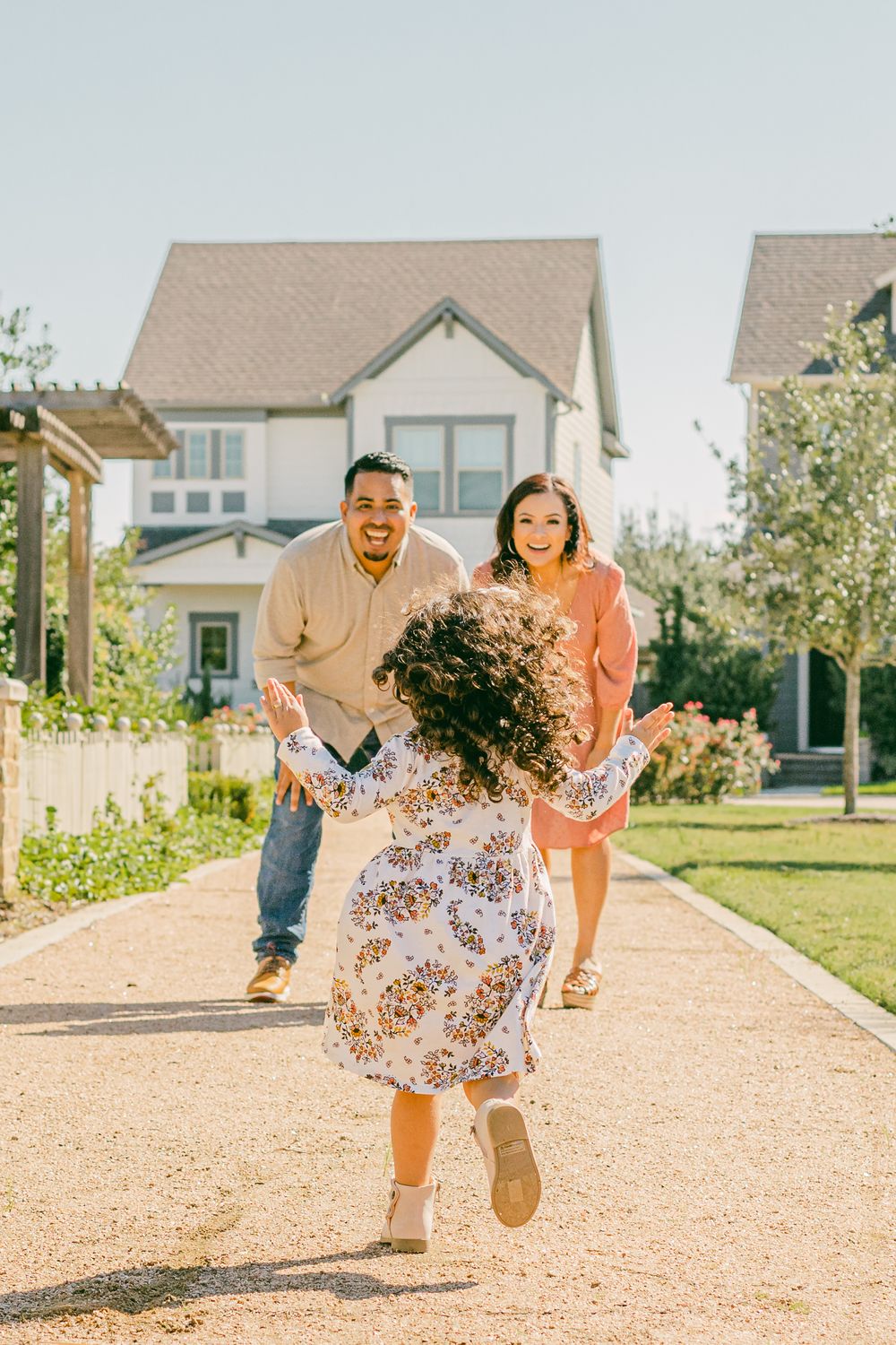 a little girl energetically runs towards her parents with outstretched arms