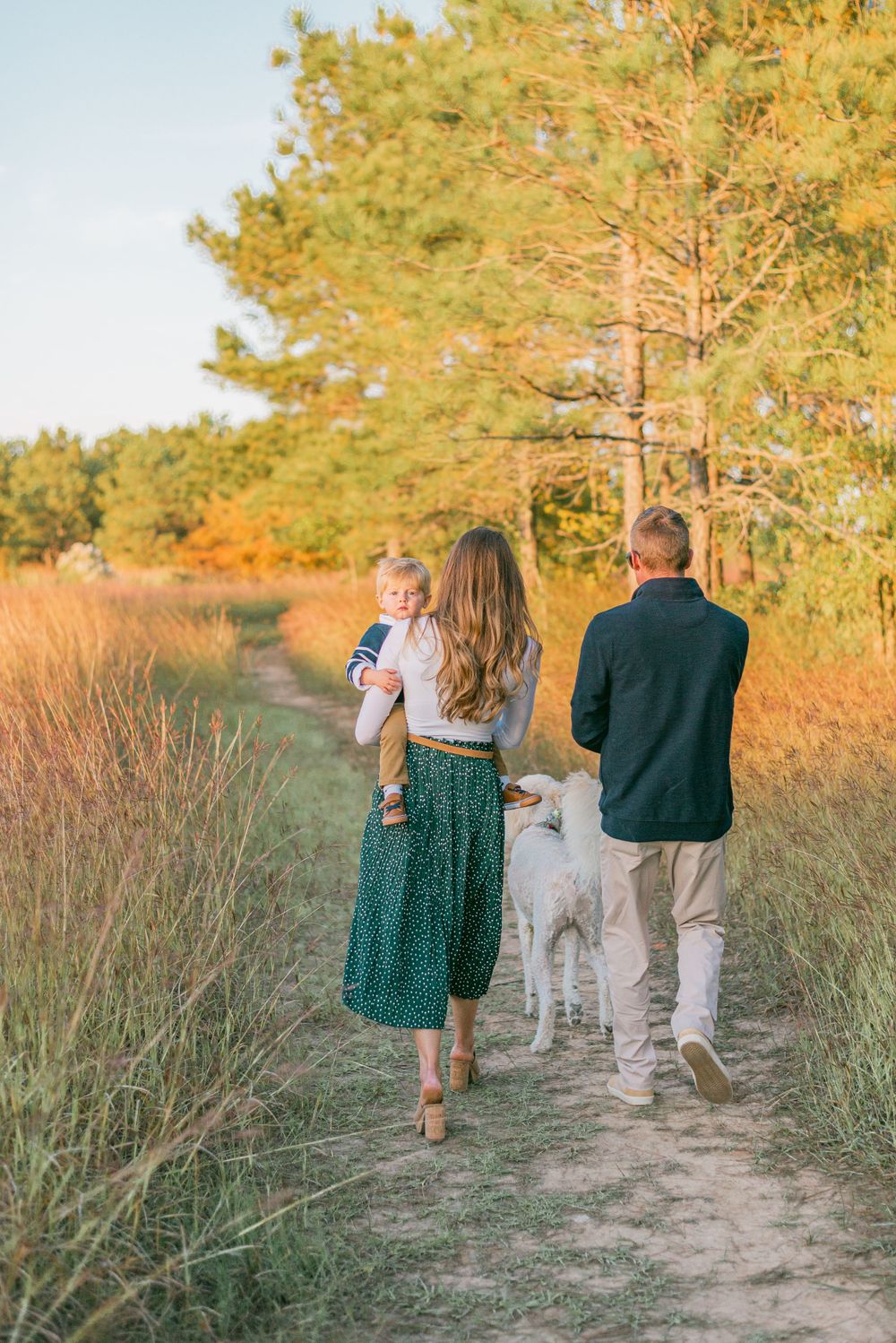 parents walk down a trail holding their baby, who looks at the camera