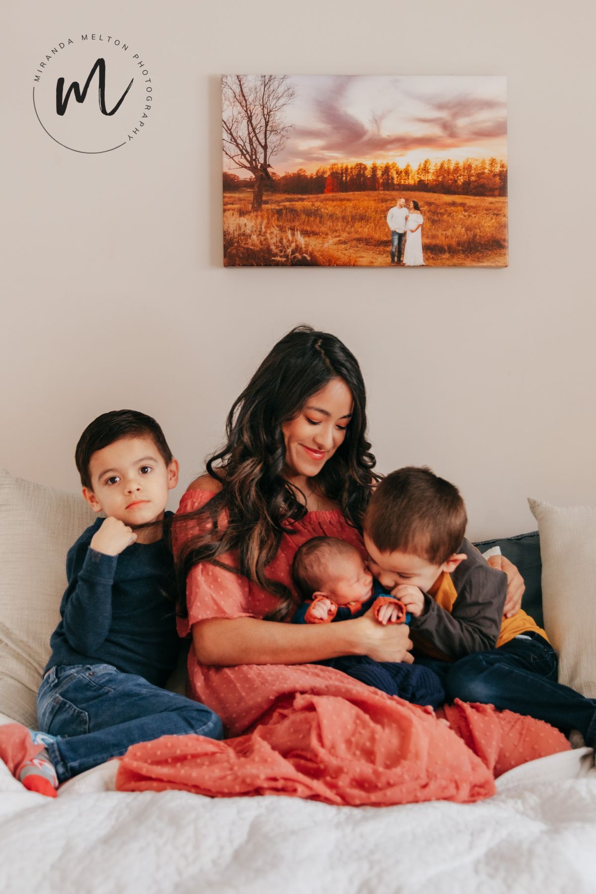 A professional family photo of a mother with her newborn and two older children cuddling at their home in Prior Lake, MN