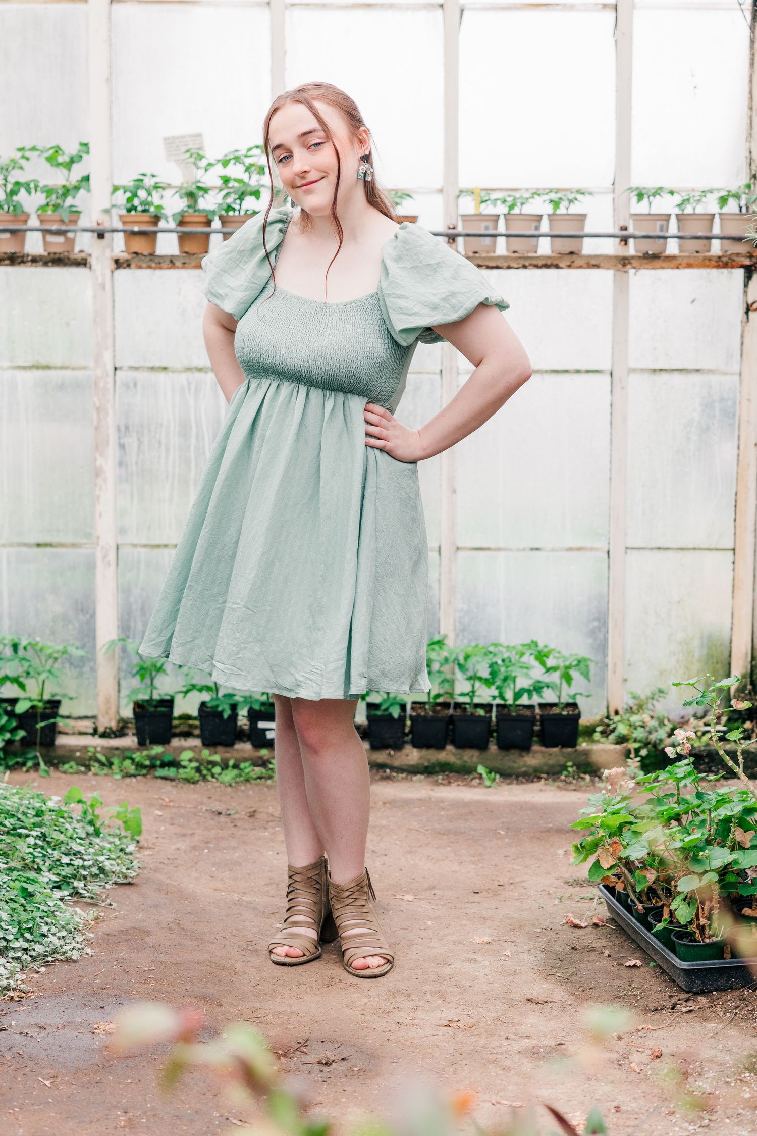Fashion portrait in a greenhouse featuring a mint green dress and brown sandals.