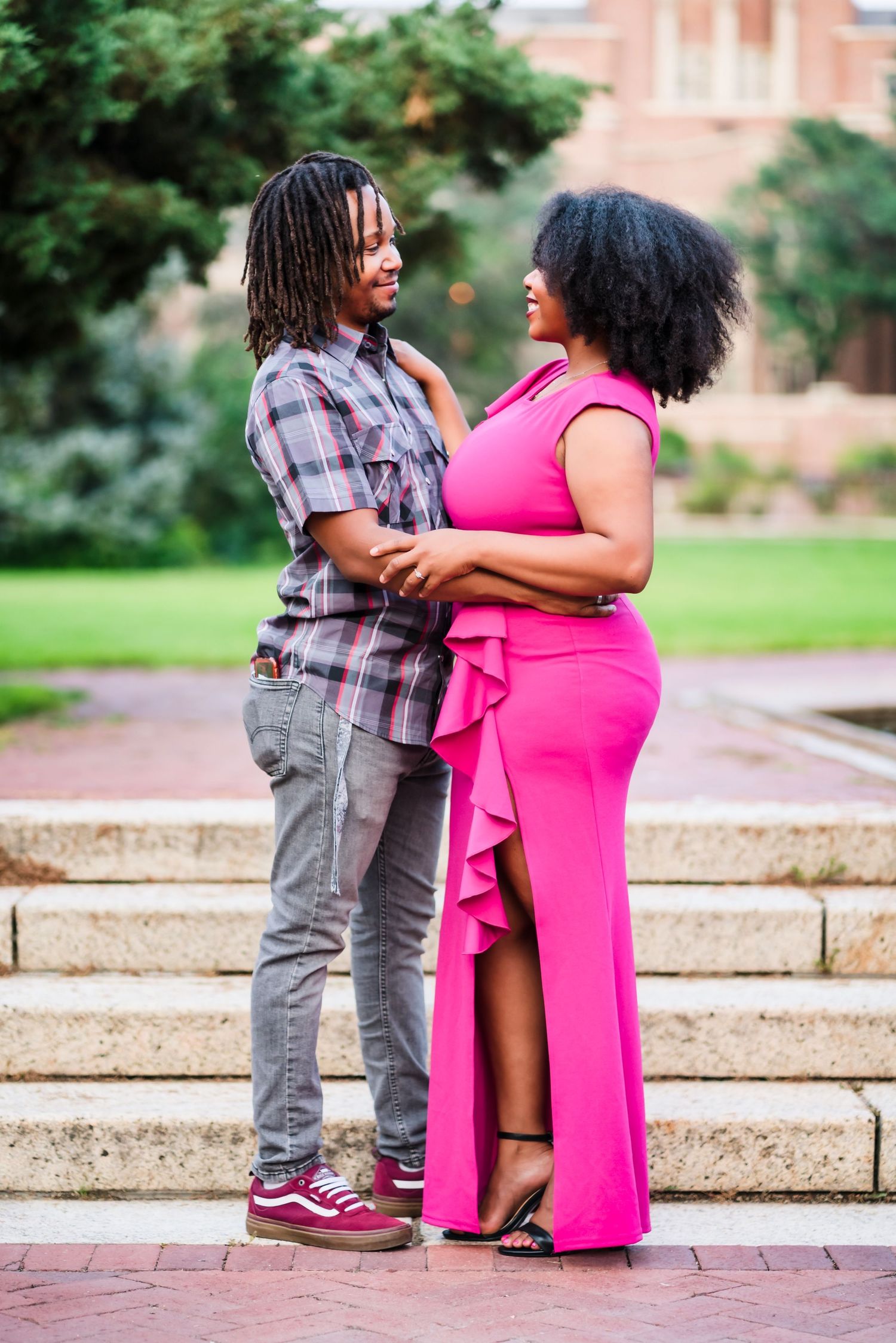 A couple poses on brick steps wearing casual and formal attire during an engagement photoshoot.