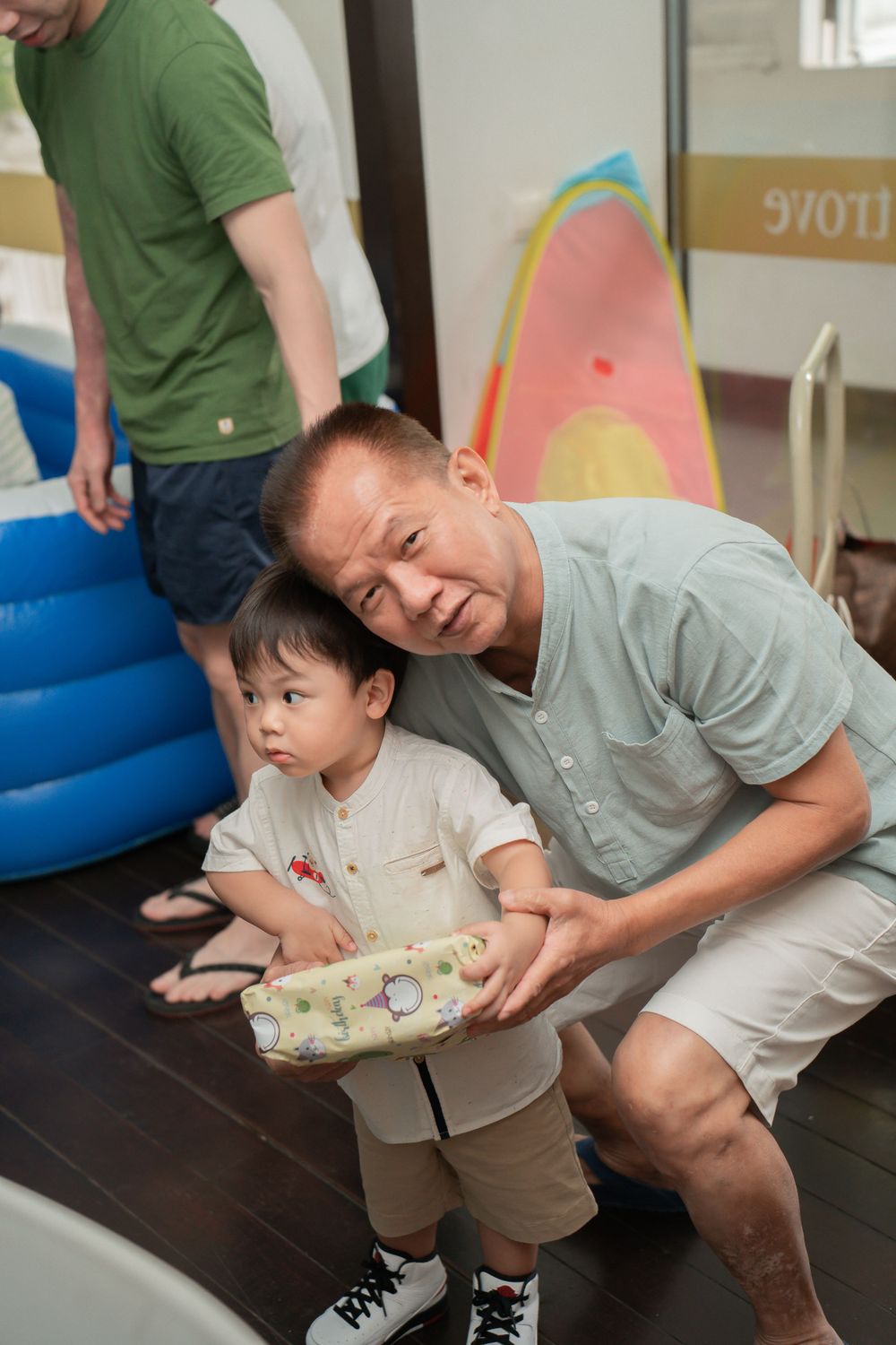 A playful moment captured during a birthday party with inflatable decorations visible in the background.