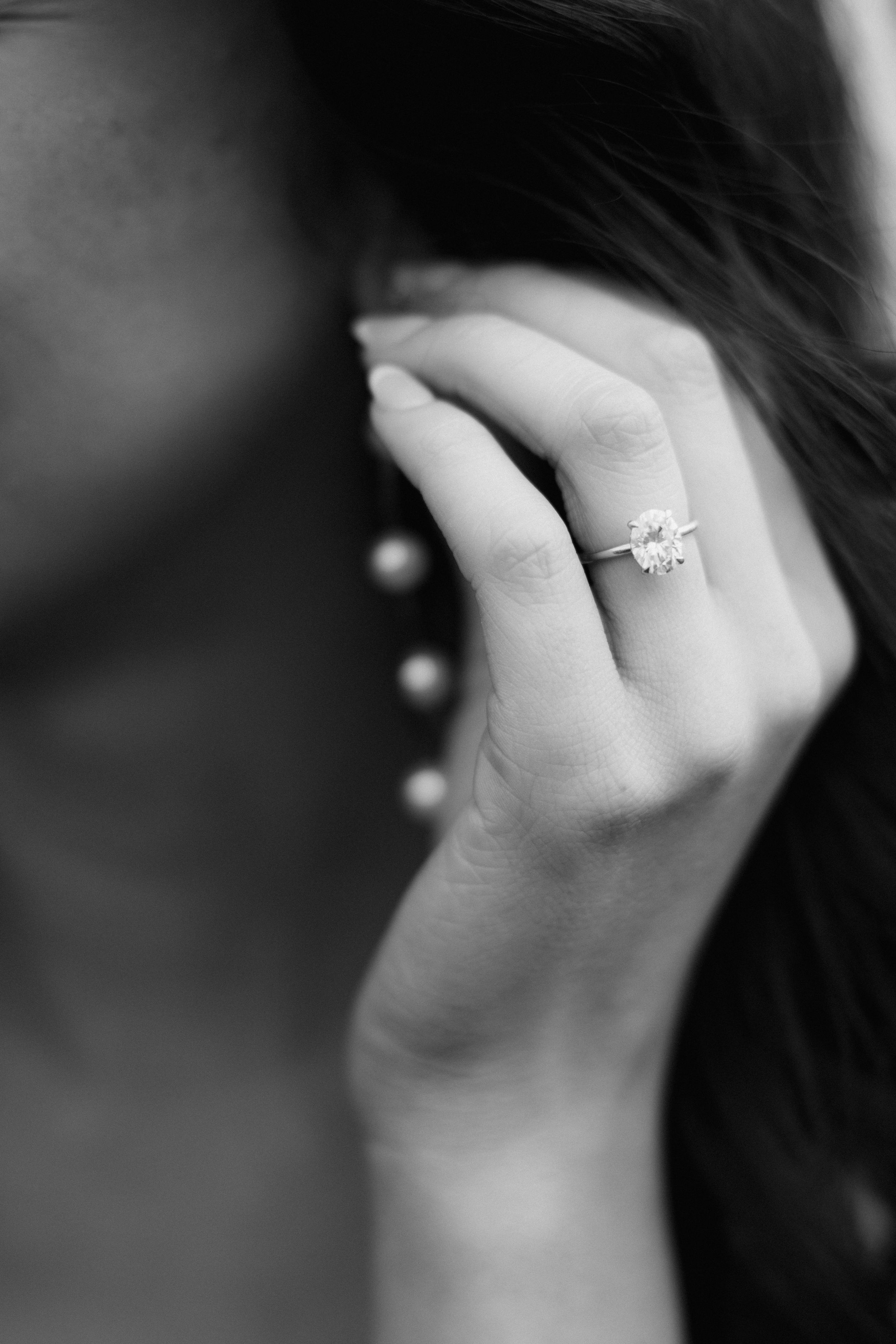 Close-up black and white shot of engagement ring on hand.