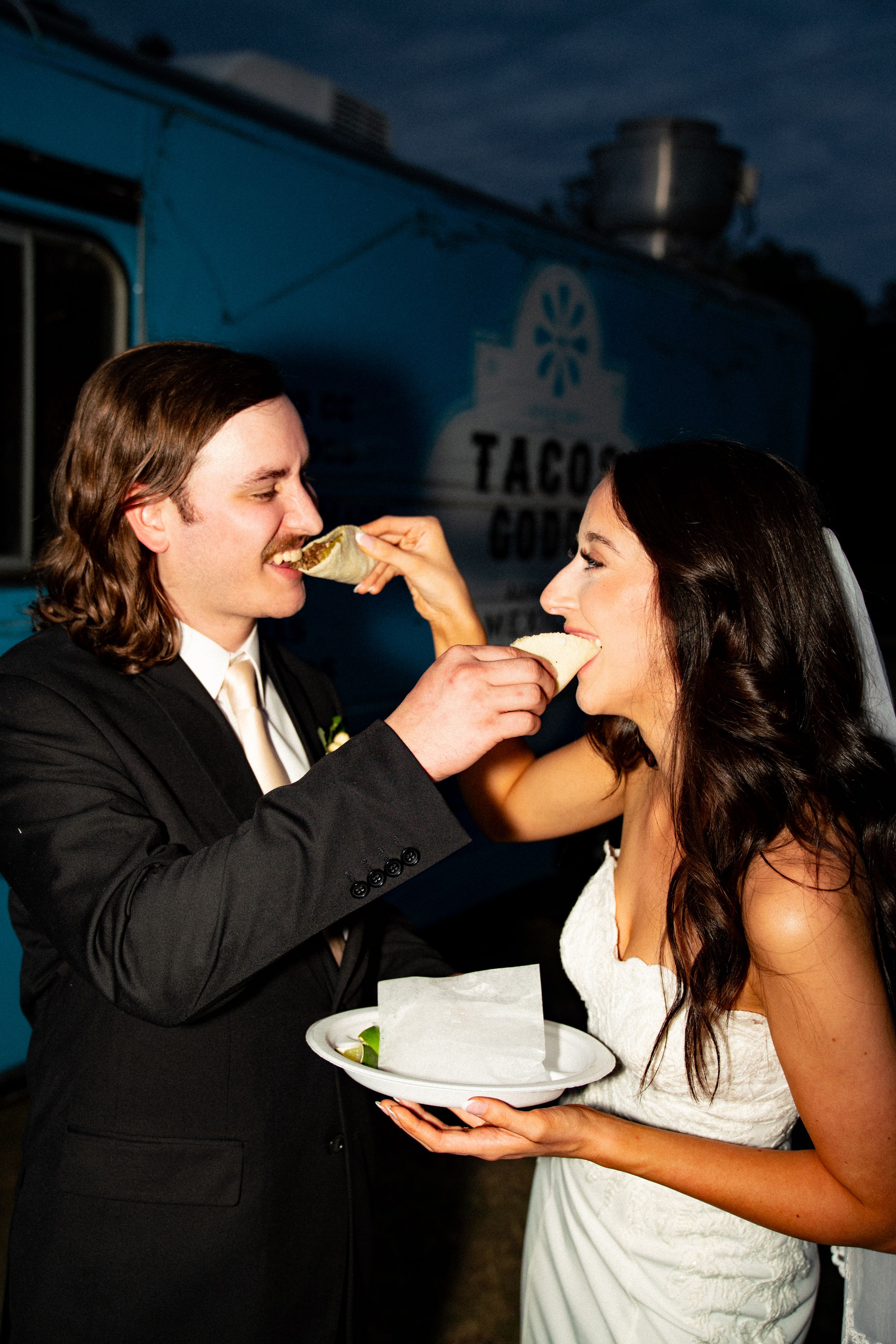 Couple playfully feeds each other tacos at their wedding reception.