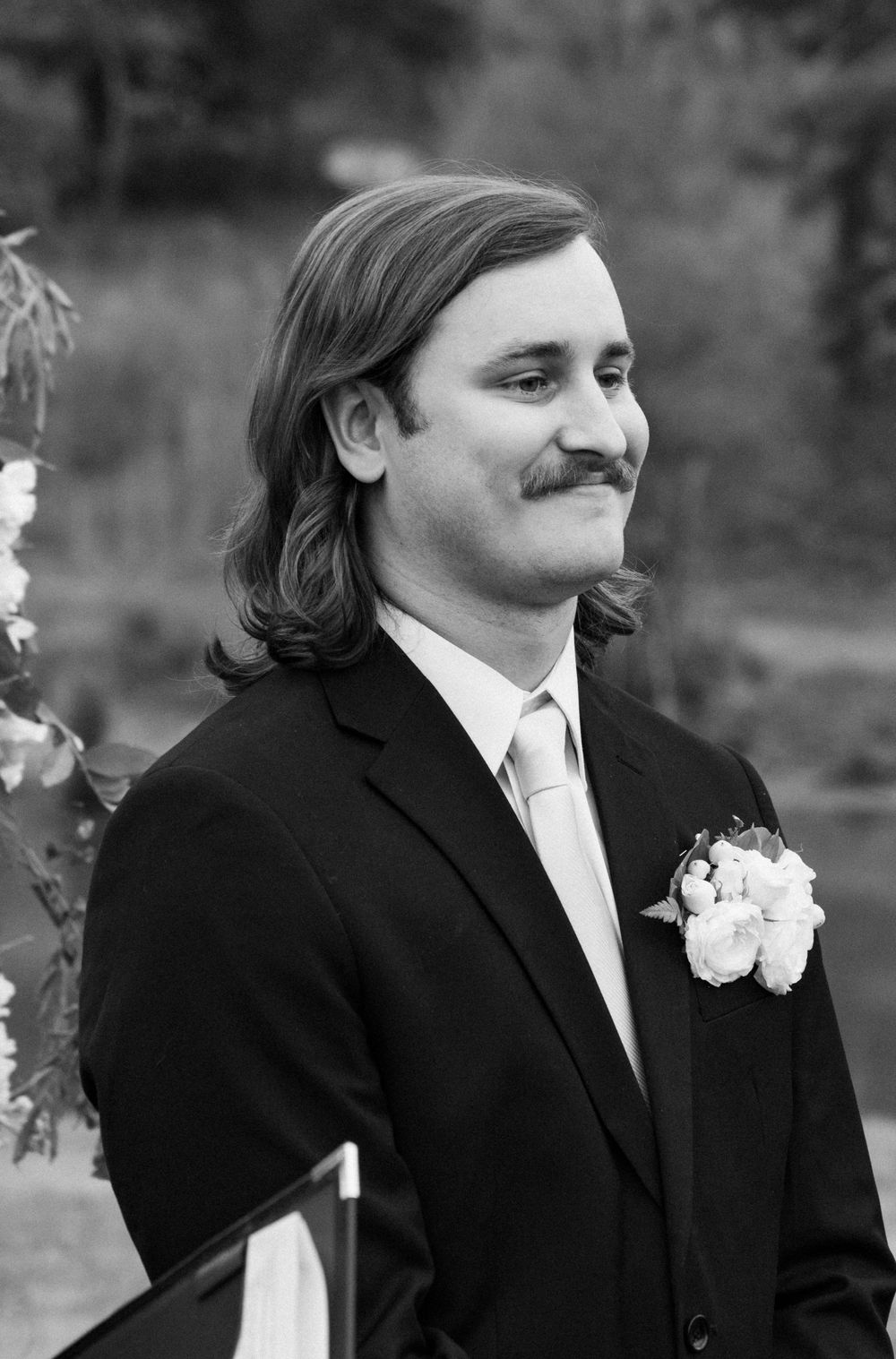Black and white portrait shots of a person in a tuxedo smiling at different angles.