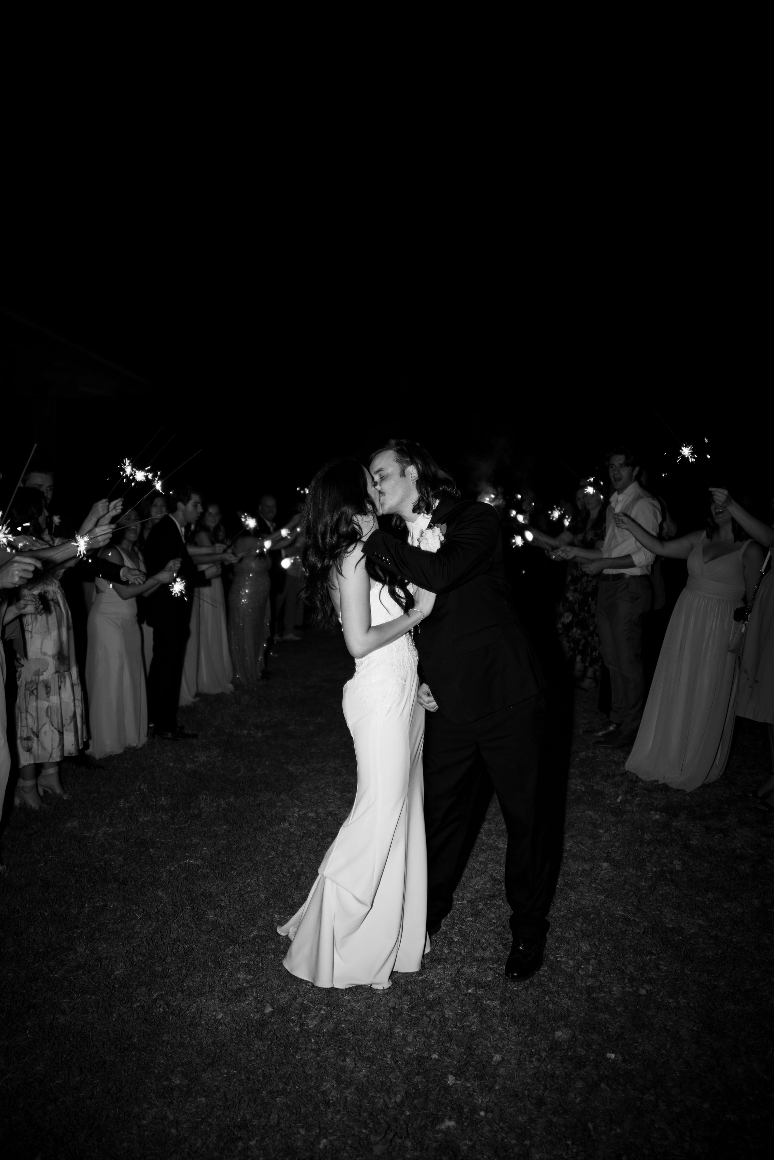Couples dancing under string lights at an outdoor evening wedding reception.