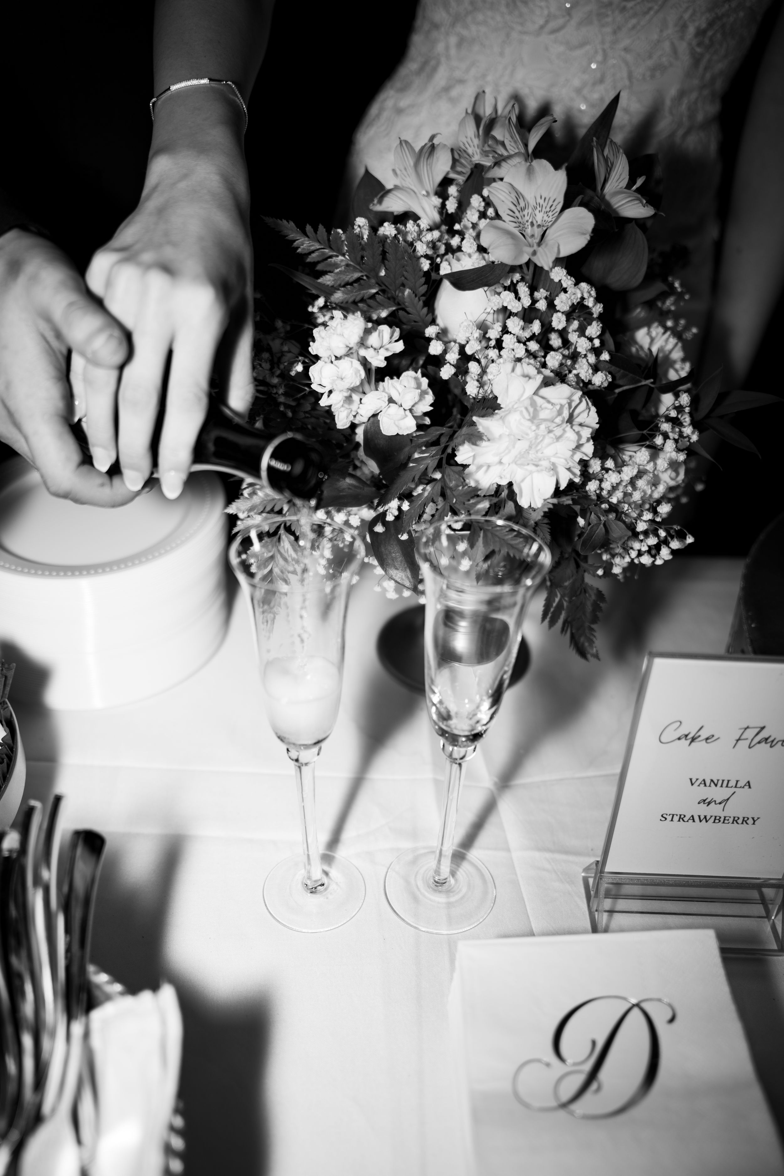 Black and white photo of elegant table settings with floral centerpieces and menu cards.