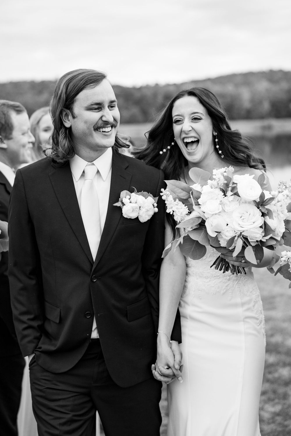 A joyful couple laughs together during their outdoor wedding photoshoot.